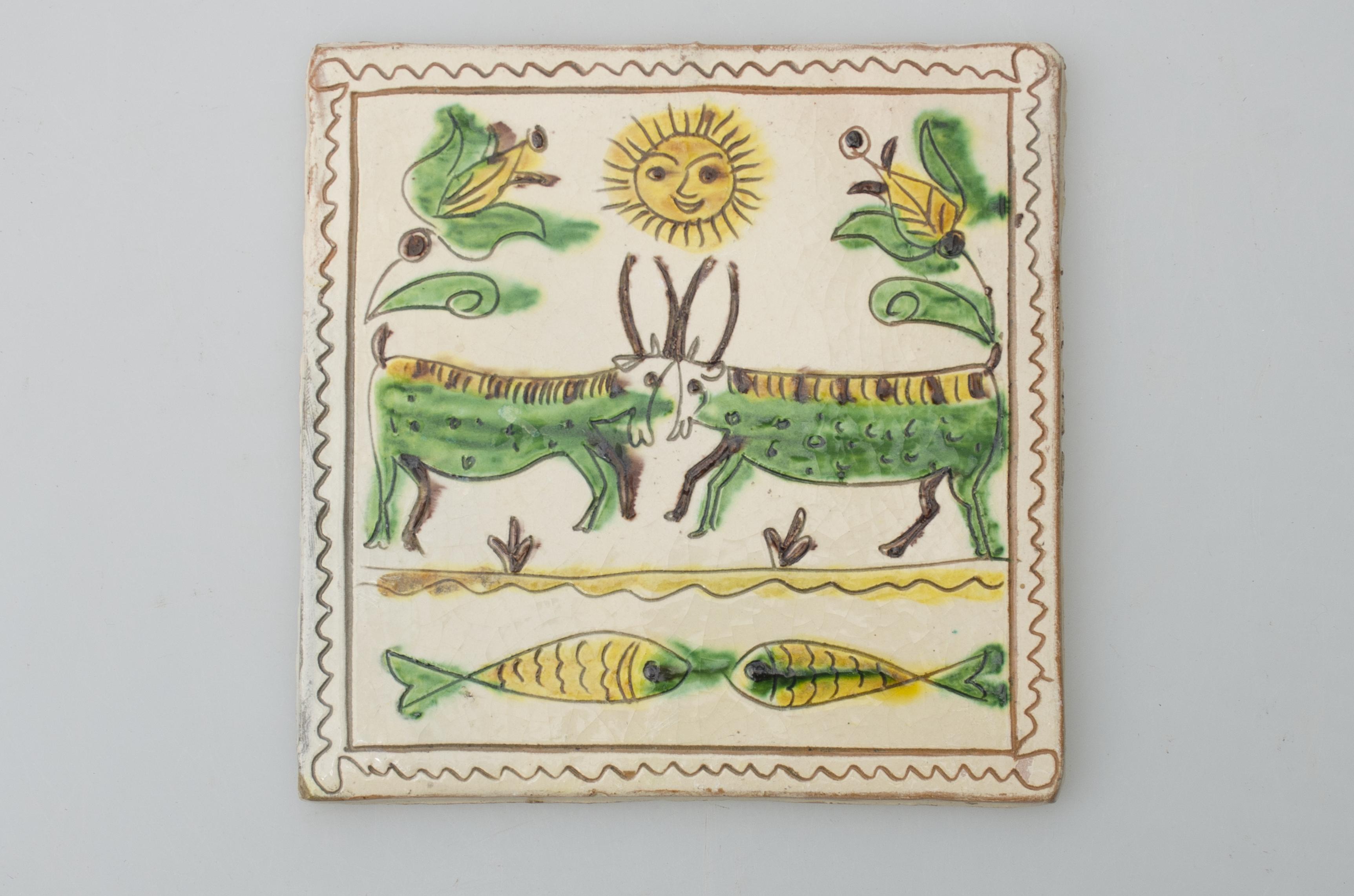 Piesă ceramică de formă pătrată, smălțuită și angobată, cu rol decorativ. Laturile pătratului sunt marcate de două chenare, primul vălurit, al doilea în linie dreaptă. Motiv: o linie dreaptă secondată de una vălurită figurează malul unui râu. În râu se ciocnesc doi pești; pe malul râului se ciocnesc doi cerbi. Deasupra lor soarele încadrat de două lalele. Motivele au fost la început incizate, iar apoi pictate. Pe spate, cahla este prevăzută cu un orificiu pentru prinderea aței. Tot aici, este inscripționat numele meșterului olar, "Colibaba". Cromatică: fond: alb; motive: verde, galben, cărămiziu, maro, negru.