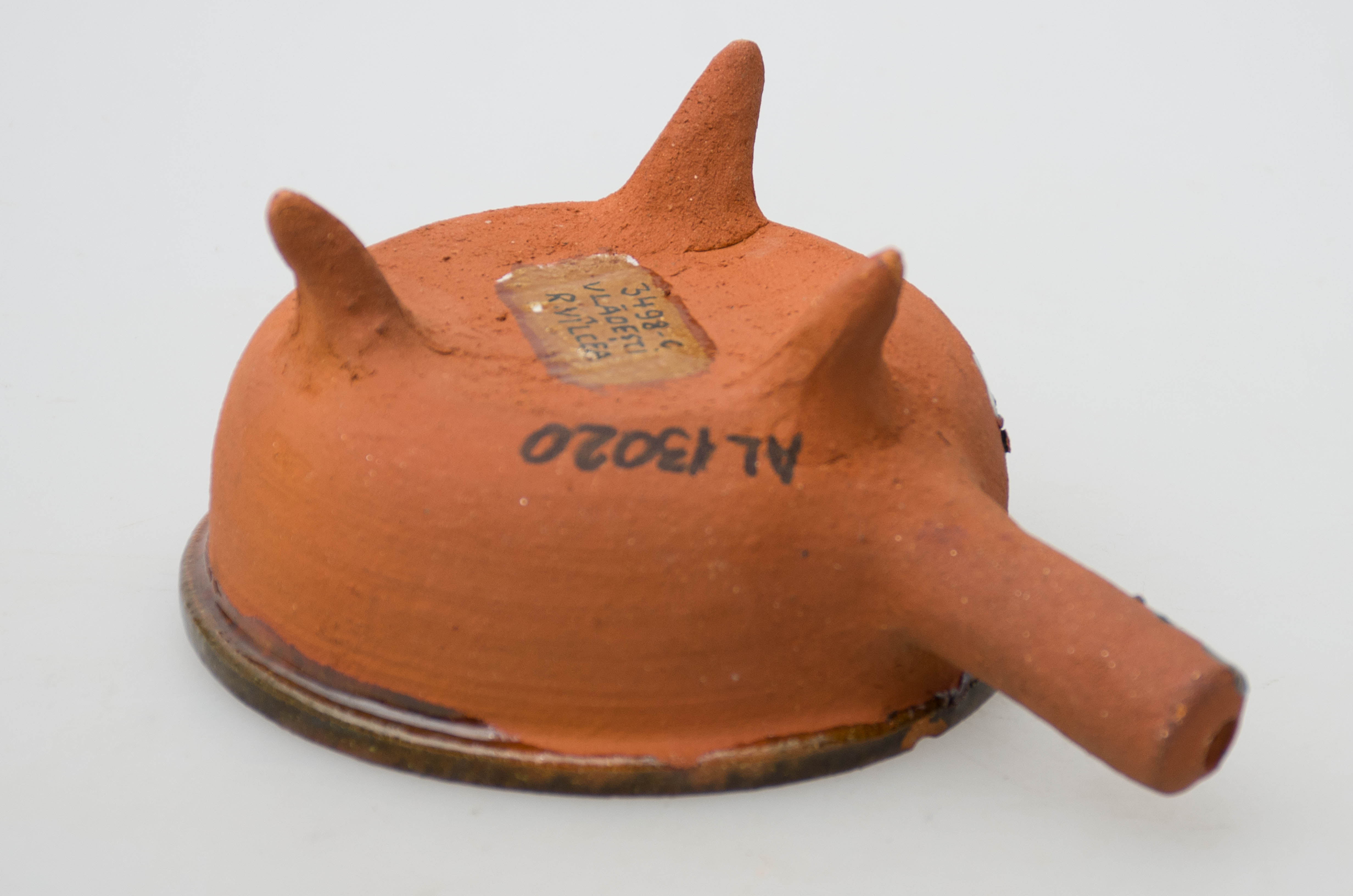 Vasul ceramic are formă circulară, având profil tronconic, cu buza reliefată și rotunjită. Acesta este prevăzut în partea inferioară cu trei piciorușe ascuțite și pe o laterală cu un mâner gros, tubular. Pe fundul vasului este decorat cu motive geometrice: puncte galbene care alcătuiesc o spirală. Obiectul prezintă smalț la interior și pe buză. Cromatică: fond: cărămiziu; motive: galben.