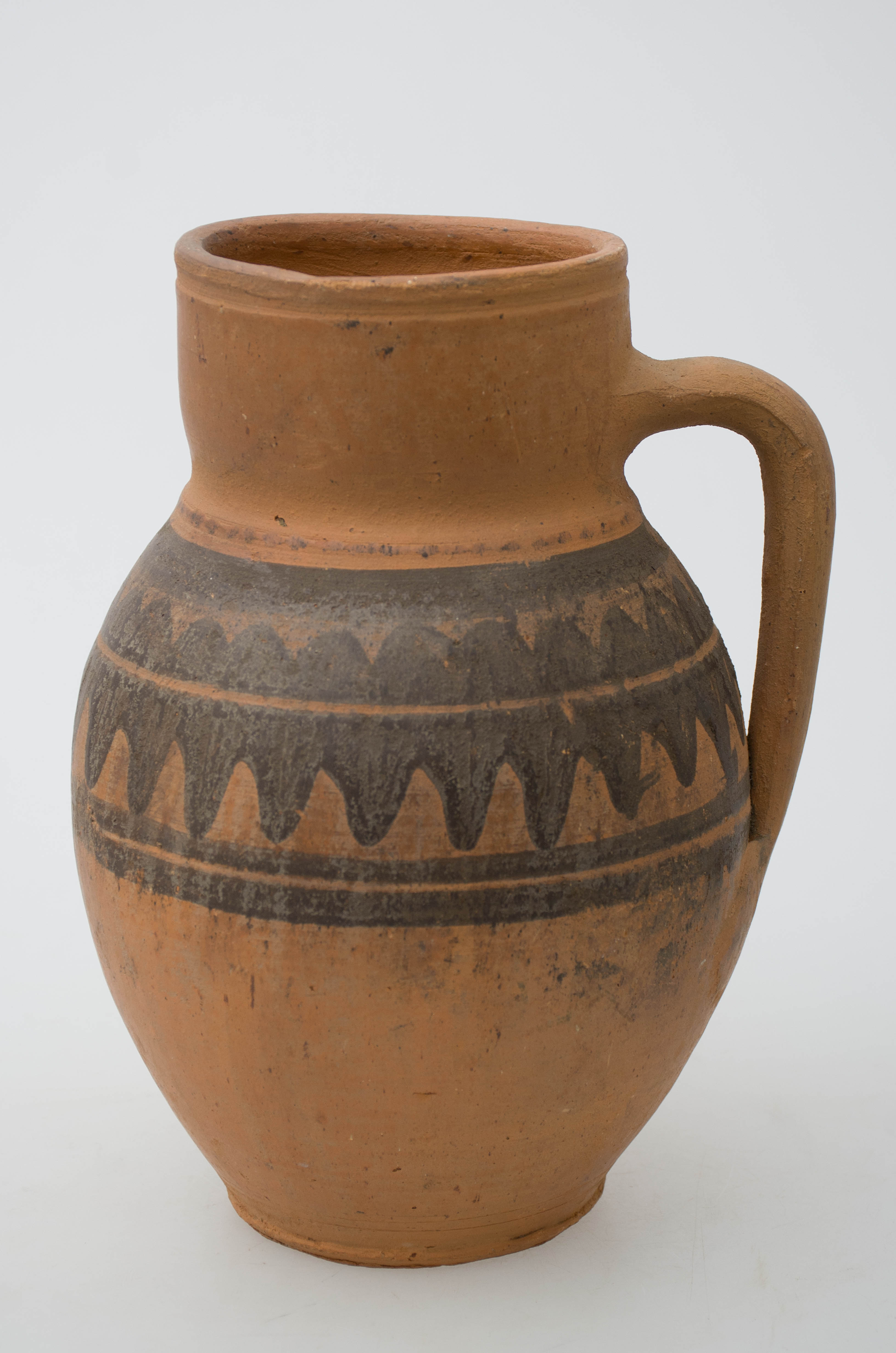 Vasul ceramic nesmălțuit are formă sferoidală, având gâtul înalt și buza dreaptă. Acesta este prevăzut cu o toartă lată și arcuită care pleacă din gât și se termină în zona inferioară. Vasul este decorat în partea mediană cu motivul dintelui de lup, încadrat între linii circulare (dispuse una sus și două jos), pictate cu humă neagră. Pe toată suprafața, recipientul este ușor șlefuit cu piatra. Cromatică: fond: cărămiziu; motive: negru.