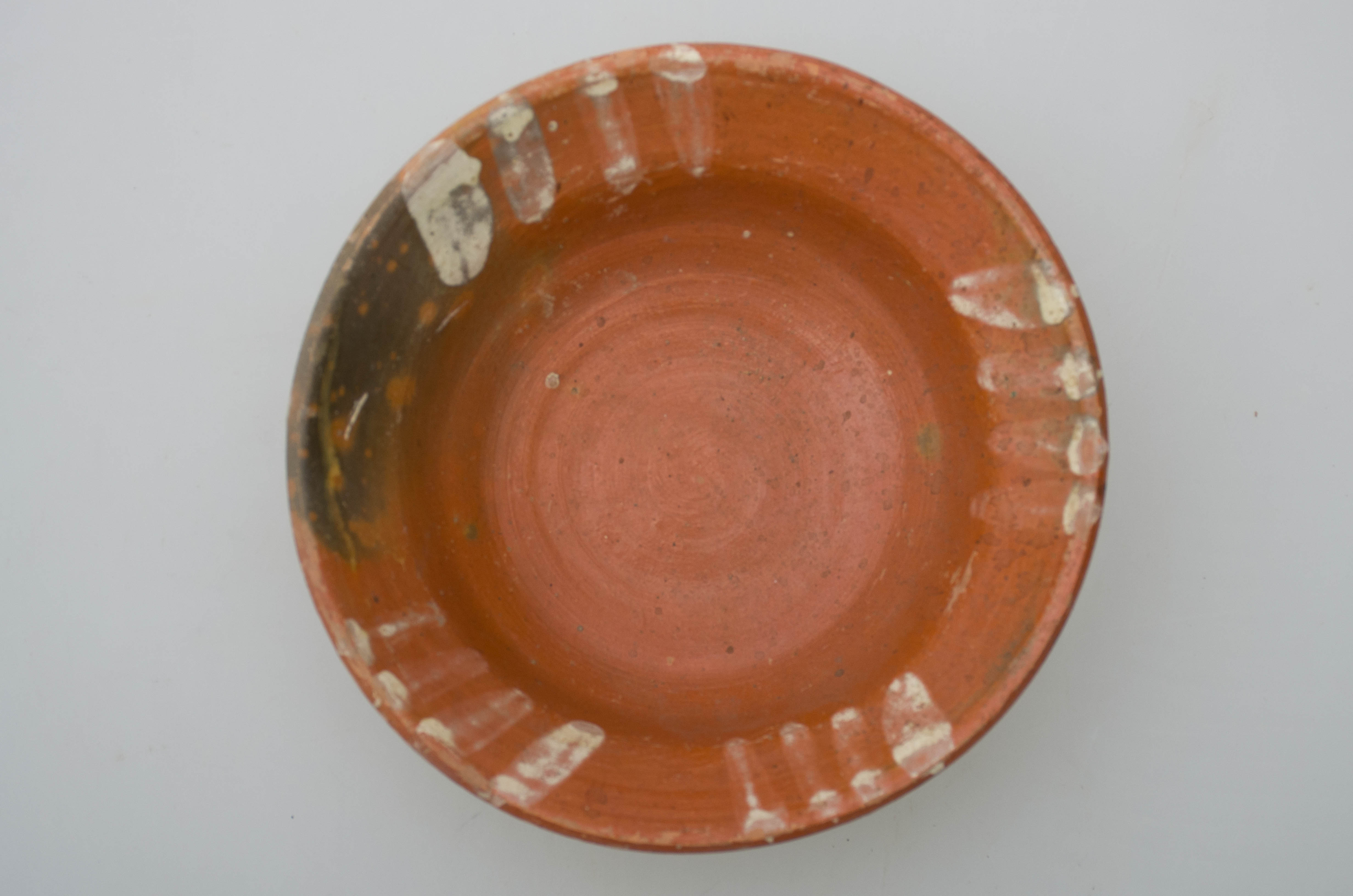 Vas ceramic de mici dimensiuni, smălțuit în interior, de formă tronconică, cu marginile puțin evazate, fundul plat și buza circulară. Pe fond verde, vasul este decorat cu motive geometrice: patru rânduri a câte patru linii prelinse șterse, pictate cu pensula. Prezintă urme de uzură funcțională. Cromatică: fond: cărămiziu; motive: alb.