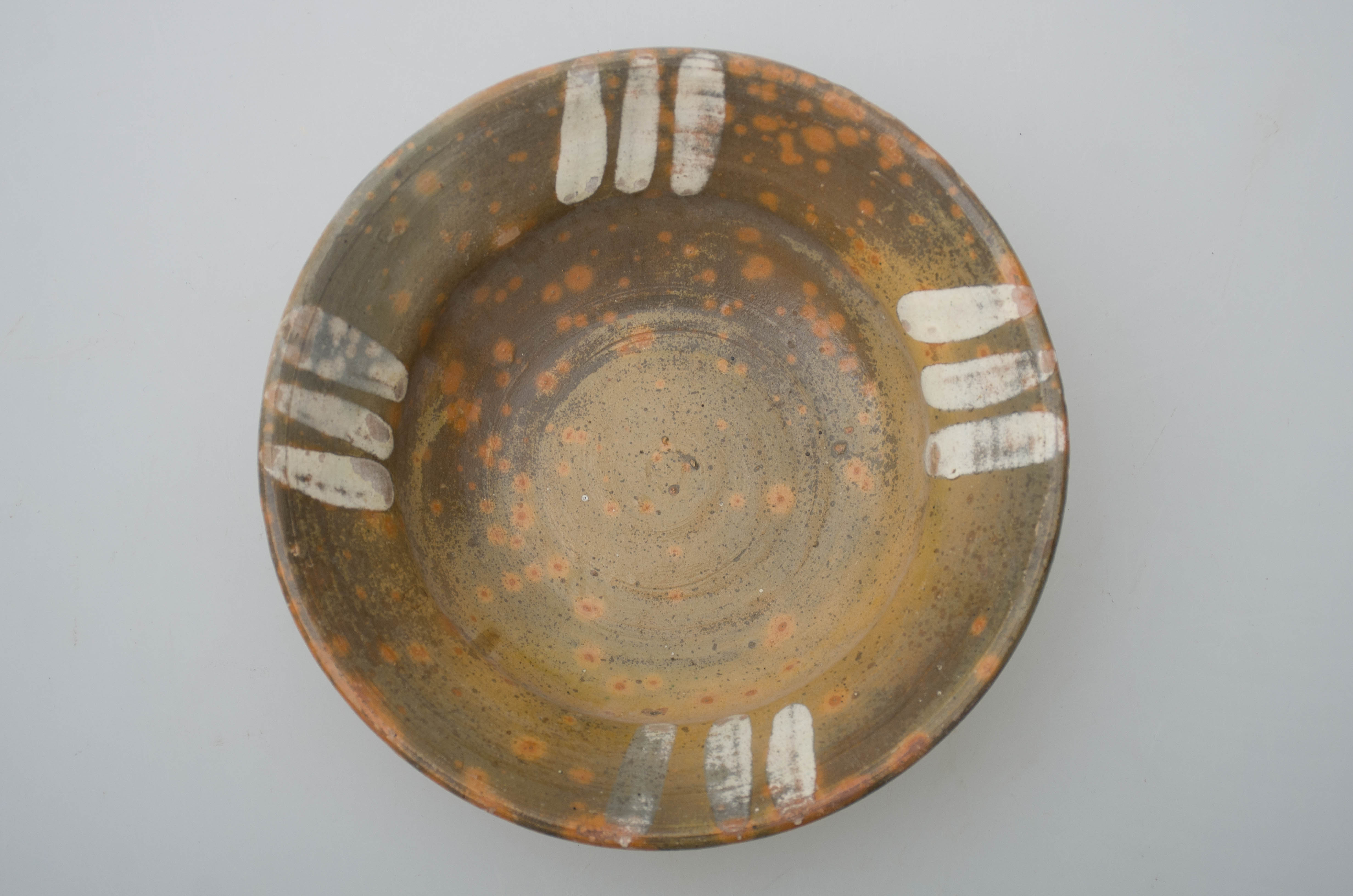 Vas ceramic de mici dimensiuni, smălțuit în interior, de formă tronconică, cu marginile puțin evazate, fundul plat și buza circulară. Pe fond ocru, vasul este decorat cu motive geometrice: patru rânduri a câte trei linii prelinse, pictate cu pensula. Prezintă urme de uzură funcțională. Cromatică: fundal ocru; motive: alb.