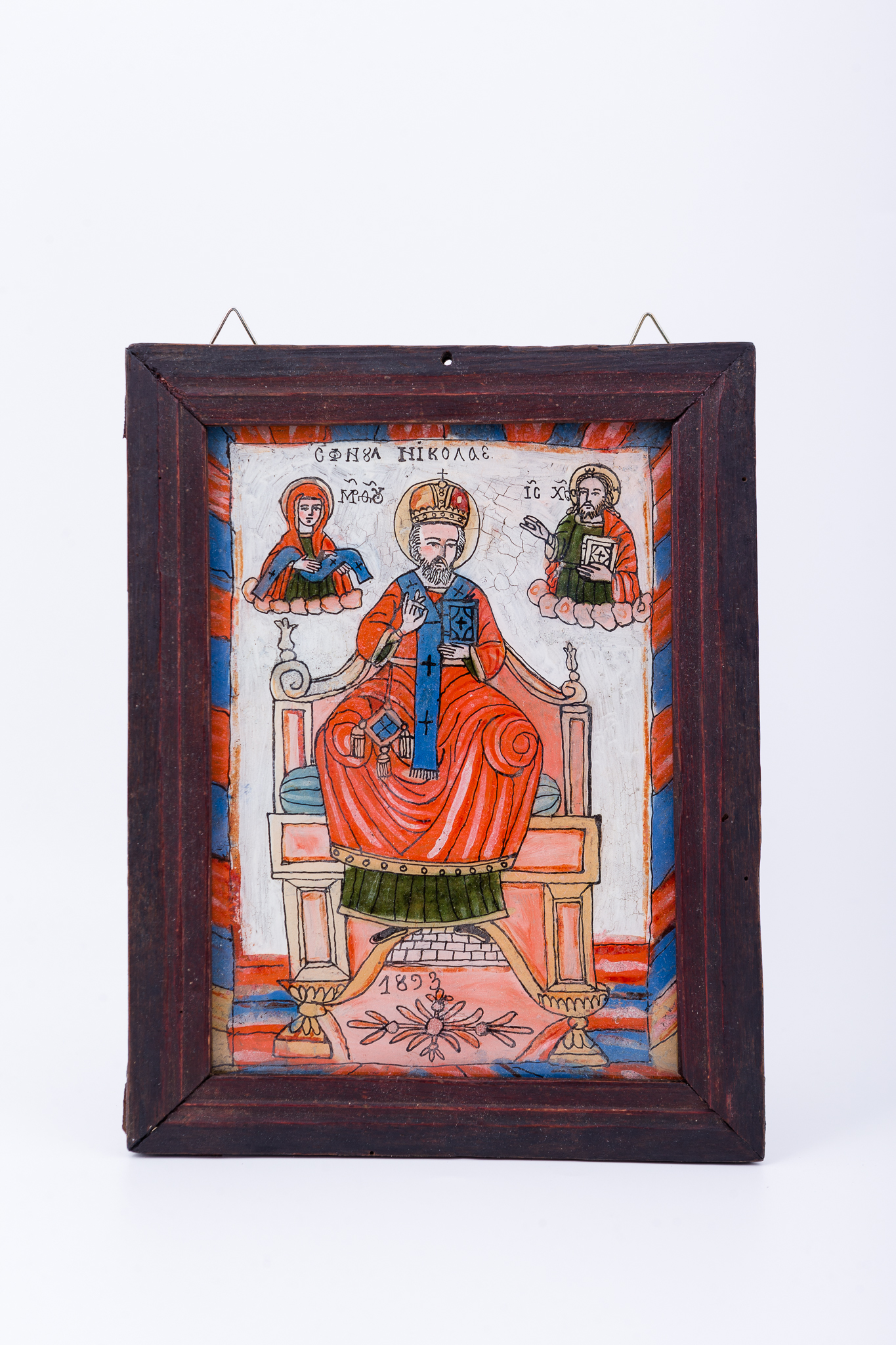 Sfântul Mare Ierarh Nicolae, făcător de minuni, îmbrăcat în veșminte liturgice, de ierarh, sacos roșu-vermillon, epitrahil-patrafir albastru ceruleum regal, cu patru cruci negre. Este supradimensionat, ocupând mai multe niveluri, ține în mâna stângă Sfânta Evanghelie închisă și cu dreapta Binecuvântează. Este unul dintre cei mai populari și iubiți sfinți, ocrotitor al caselor, familiilor și copiilor. Are barbă sură și mithră arhierească și aureolă. Fondul este alb-ivoriu, cu radiații roz. În registrul superior este Dumnezeu-Tatăl binecuvântând și Maica Domnului ocrotind. Cromatica este armonioasă și serafic-diafană: roșu vermillon, roz, albastru ceruleum regal, verde mușchi de pădure, ivoriu, gri, ocru, bej, negru, alb. Inscripția din româno-chirilică se traduce Sfântul Nicolae MP Maica Domnului IC XC Iisus Hristos. Icoana este datată 1893. Icoana este pictată de Matei Țimforea, din Cârțișoara, Țara Făgărașului.