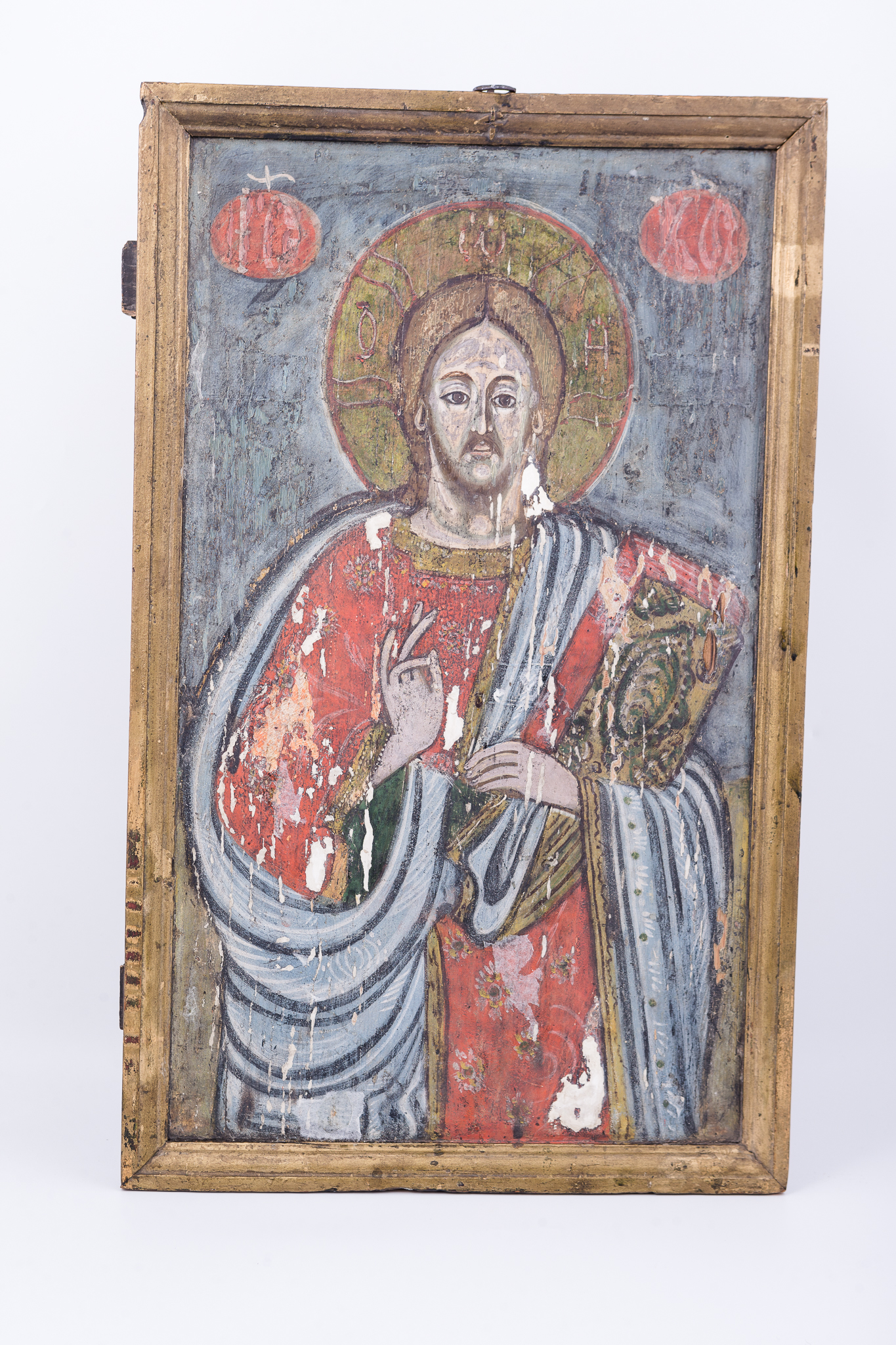 Mântuitorul Iisus Hristos Pantocrator este tematica iconografică pictată, de obicei, pe bolta bisericii. Pantocrator înseamnă Atotțiitor, AtotStăpânitor. De aceea este și pictat pe locul cel mai înalt al unei biserici, binecuvântând de sus toată lumea care intră în sălașul sfânt de rugăciune. Această tematică iconografică este redată în această icoană de iconostas. Iisus Hristos este înveșmântat într-o mantie-omofor albastră bleu-ciel, cu sacos interior roșu vermillon, cu bordură dantelată bronzie. În mâna stângă ține Sfânta Evanghelie închisă. Cu mâna dreaptă binecuvântează. Veșmântul Mântuitorului este împodobit cu elemente florale punctiforme aurii. Desenul este de o acuratețe impresionantă și cromatica este armonioasă. Icoana este după un model bizantin. Inscripția din româno-chirilică se traduce IC XC Iisus Hristos. Cromatica este armonioasă: roșu vermillon, albastru bleu-ciel și ceruleum, bronziu, brun, alb, negru.