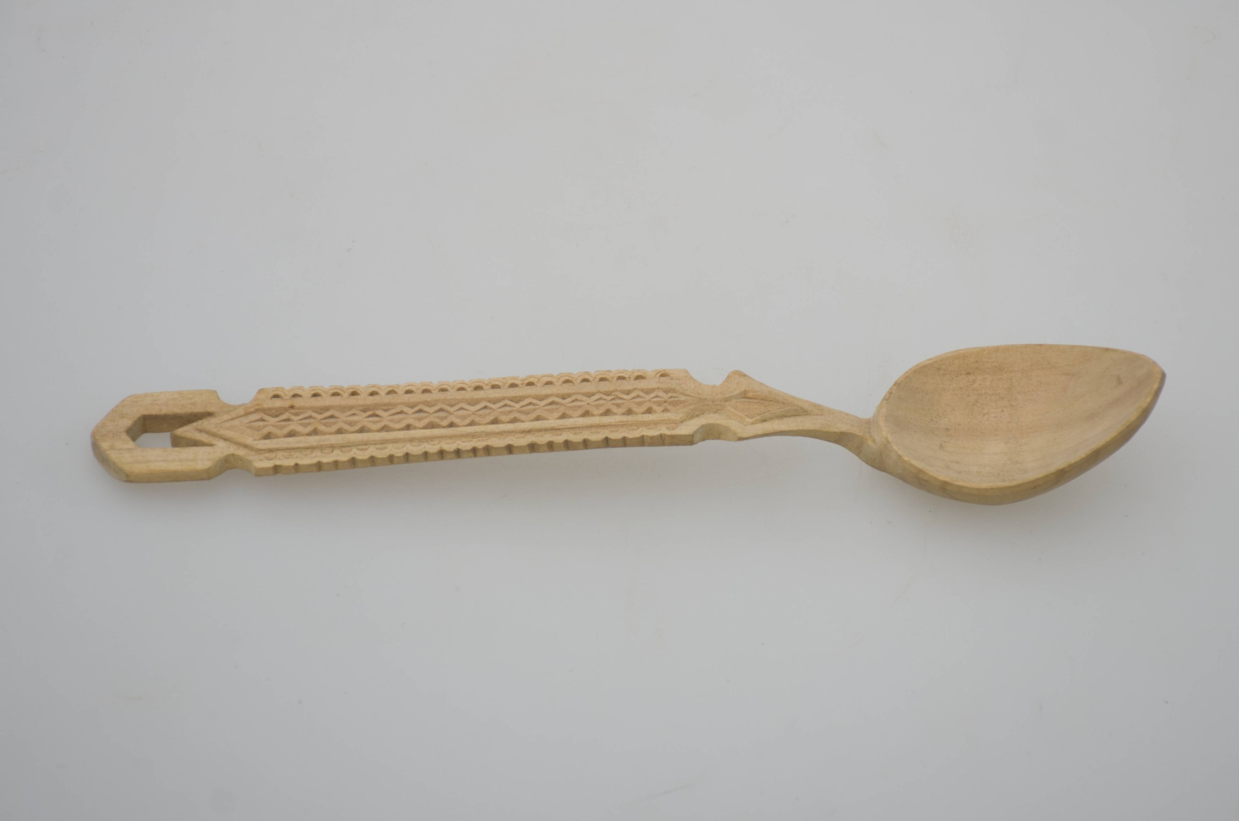 Piesă alcătuită dintr-un căuc oval și o coadă lungă ce se îngustează spre câuc și prezintă un decupaj la capătul opus. Ornamente incizate sub formă de linii drepte, frânte și semicercuri dispuse pe lungimea cozii. Cromatică: culoarea naturală a lemnului.