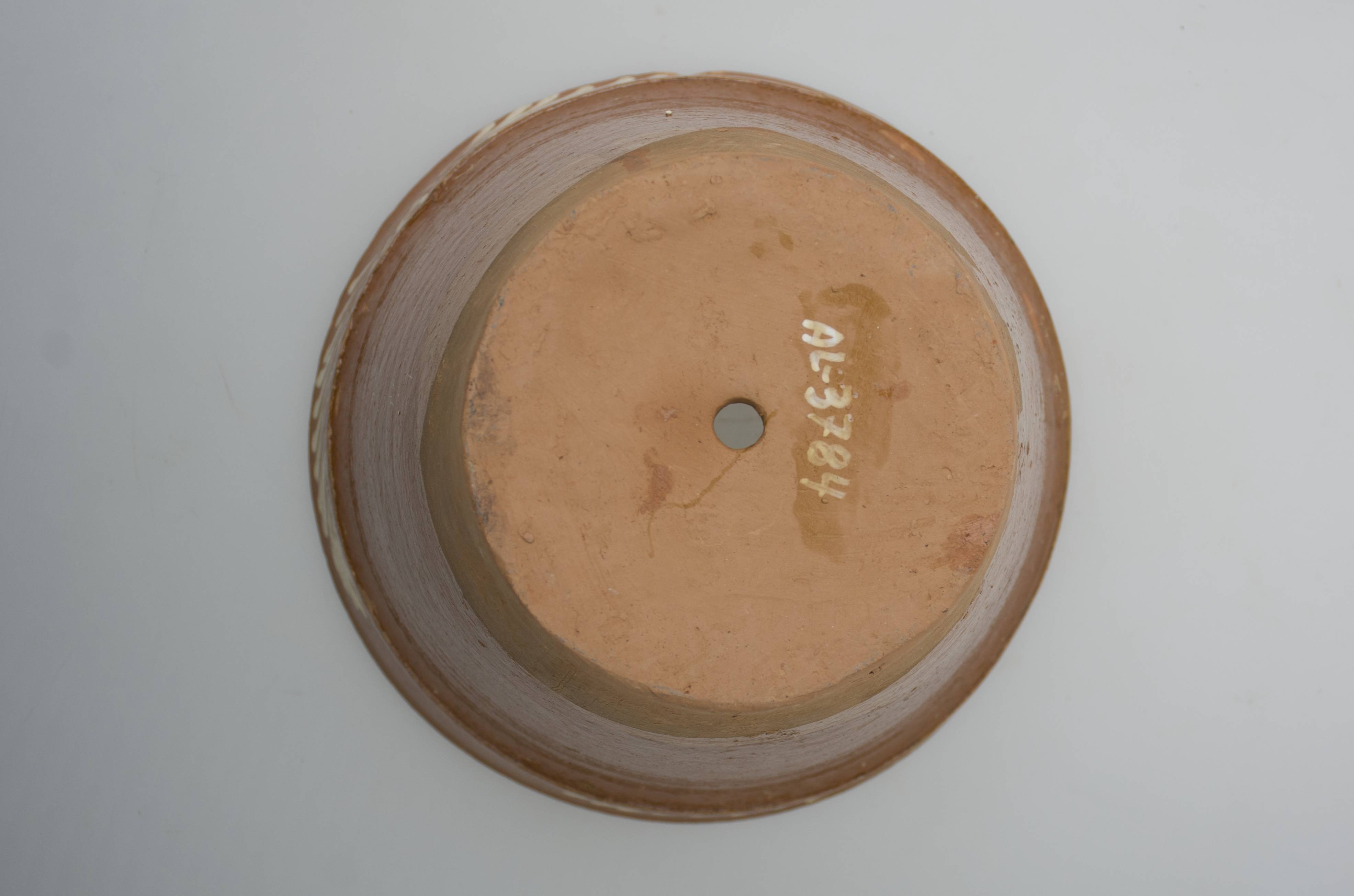 Vas ceramic de uz casnic, cu rol decorativ, întrebuințat în gospodărie ca ghiveci pentru flori. Recipient de formă tronconică, cu gura mai largă decât baza, buză îngroșată, dreaptă, înaltă și trasă spre exterior. Bază plată este prevăzută cu un orificiu pentru scurgerea apei. Vasul este smălțuit la exterior de la buză până aproape de fund (3/4). Pe buză, la exterior, se identifică un decor pictat cu motive vegetale (ornamentată marginea cu "vinci"). La interior este nesmălțuit. Vasul a fost ars în tehnica arderii oxidante. Cromatică: fond: cărămiziu; motive; alb.
