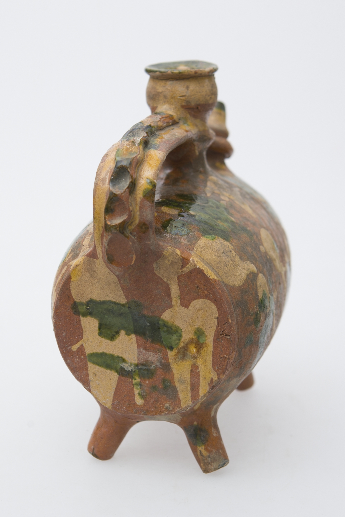 Recipient ceramic sub formă de butoiaș cilindric, dispus pe orizontală, asemănător corpului de rață. Sprijinit pe patru picioare tubulare dispuse oblic câte două la capete. Prezintă toartă. Scurgere printr-un cioc cu vârful conic care este legat prins printr-un inel de mijlocul gâtului cilindric și strâmt dispus la mijlocul vasului, având la capăt reliefată o față umană în relief terminată cu gura cu buză dreaptă pentru introducerea lichidelor. Opus ciocului, prezintă o toartă lată, puternic arcuită, de-a lungul căreia se suprapune, o bandă reliefață decorată prin presare cu degetul. Pe corpul vasului, dispuse aleatoriu, pete albe și de smalț verde și galben. Cromatică: fond: cărămiziu; motive: alb; galben; verde.