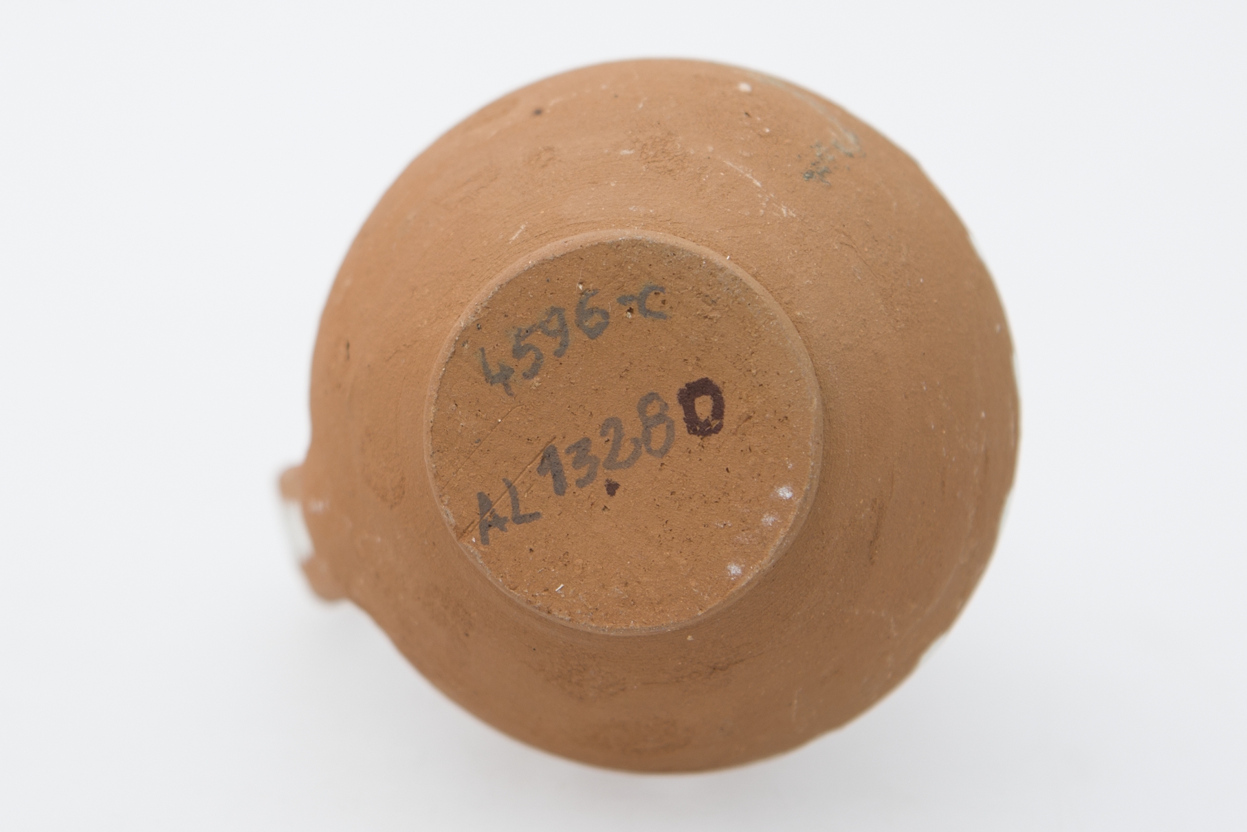 Recipient ceramic piriform pe inel de susținere pronunțat cu pântecele bombat, gâtul mai îngust și înalt, gura evazată cu buza conturată cu alb și puțin rotunjită. Toarta pornește din buză arcuindu-se larg și în lung până la mijlocul pântecului sub formă de linii în zig-zag, dispuse vertical. Cromatică: fond: culoarea lutului ars-cărămiziu; motive: alb.