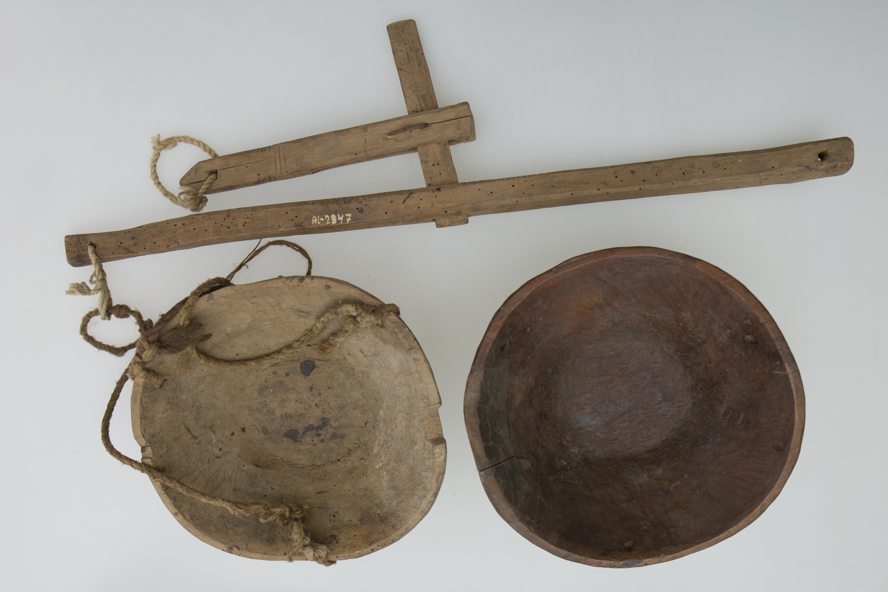 Balanță din lemn formată dintr-o pârghie în balans având la capete atârnate de sfori două talere circulare, asemănătoare unor blide din lemn. Cromatică: maro (lemn); crem (cânepă).