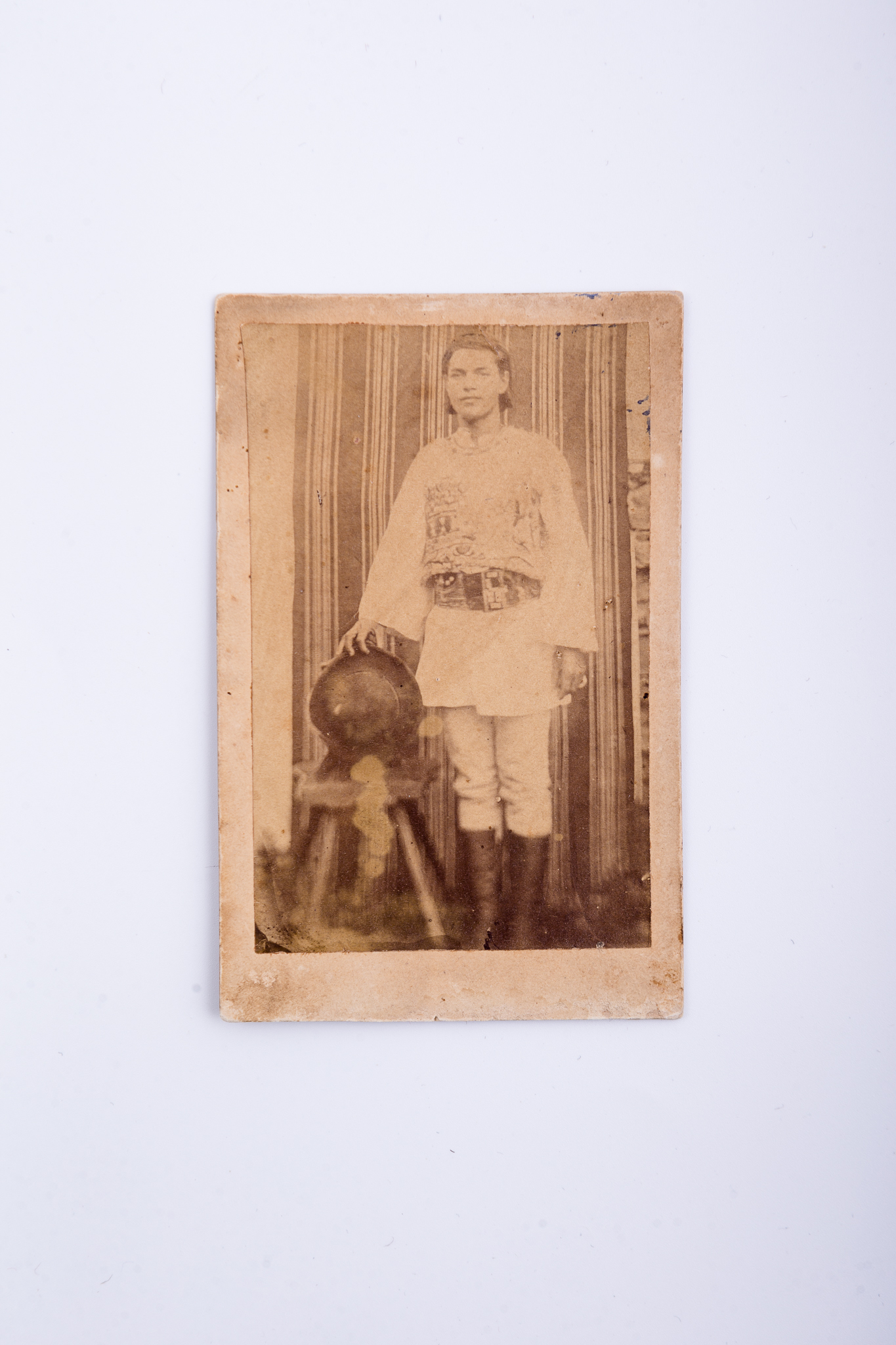 Fotografia de exterior realizată într-un atelier improvizat. În plan secund se remarcă o țesătură, cu rol de fundal, fixată pe un perete de piatră. Element de recuzită: scaun. Prezintă un tânăr în costum popular specific din Rășinari, județul Sibiu. Imaginea, realizată după un clișeu pe sticlă, este imprimată pe hârtie albuminată, după un clișeu pe sticlă. Imaginea este lipită pe un carton gros, de culoare crem. Urme de uzură funcțională: pete maro. Pe verso, însemnare manuscrisă, cu creionul: „Port din Rășinari / anul 1874”. Ștampilă: Muzeul „Brukenthal” Sibiu, Nr. 407. Numărul este tăiat. Număr de inventar MCPR 1634.