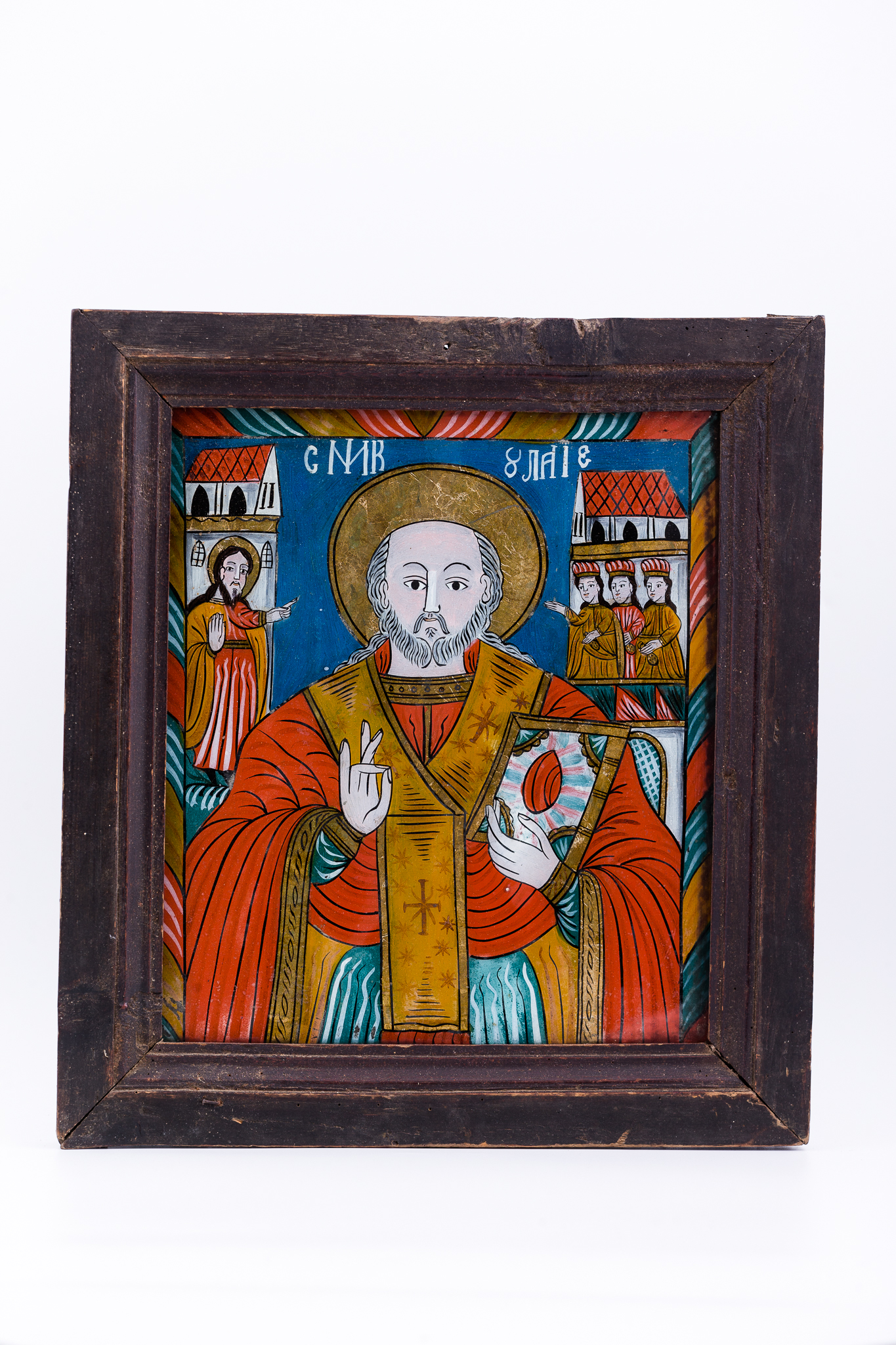 Sfântul Mare Ierarh Nicolae, făcător de minuni, este îmbrăcat în veșminte liturgice, de ierarh, sacos roșu-vermillon, ocru și verde absint, cu epitrahil-patrafir galben-chihlimbar-ocru, cu trei cruci mari brune. Sfântul Nicolae ține în mâna stângă Sfânta Evanghelie închisă și cu dreapta Binecuvântează. Este unul dintre cei mai populari și iubiți sfinți, ocrotitor al caselor, familiilor și copiilor. Are barbă sură și aureolă. Fondul este albastru regal. În dreapta Sfântului Nicolae este Mântuitorul Iisus Hristos Binecuvântând, iar în stânga sunt cele trei fete, salvate și ocrotite de ierarh. Întreaga compoziție iconografică este încadrată de un chenar decorativ geometrizant, format din linii oblice paralele, alternativ cromatizate. Sunt prezente și elemente de arhitectură, care spațializează narațiunea teologică. Un detaliu semnificativ este că Sfântul Nicolae nu are mithră arhierească. Cromatica este armonioasă și serafic-diafană: roșu vermillon, orange, albastru ceruleum regal, verde mușchi de pădure, ivoriu, gri, ocru, bej, negru, alb. Icoana este de Făgăraș. Inscripția din româno-chirilică se traduce Sfântul Nicolae.
