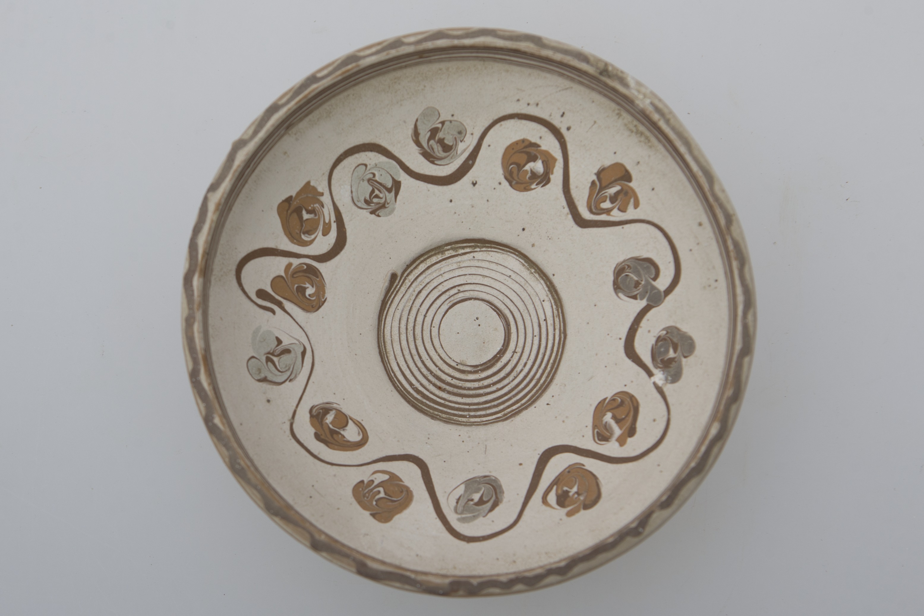 Vas de uz casnic, ceramic, de formă tronconică, ușor adâncit și buza rotunjită. Nesmălțuit și angobat. Prezintă decorații geometrice și florale pe întreaga suprafață interioară a vasului, realizate cu cornul. În centrul vasului este redată o spirală, separată de restul vasului cu o linie circulară, maro. Pe pereți, decorul continuă cu o stea cu multe colțuri, intercalată cu flori stilizate. Pe buză, tot la interior, farfuria este decorată cu benzi multiple, maro. Cromatică: fond: alb; motive: negru; gri; maro deschis; maro închis.