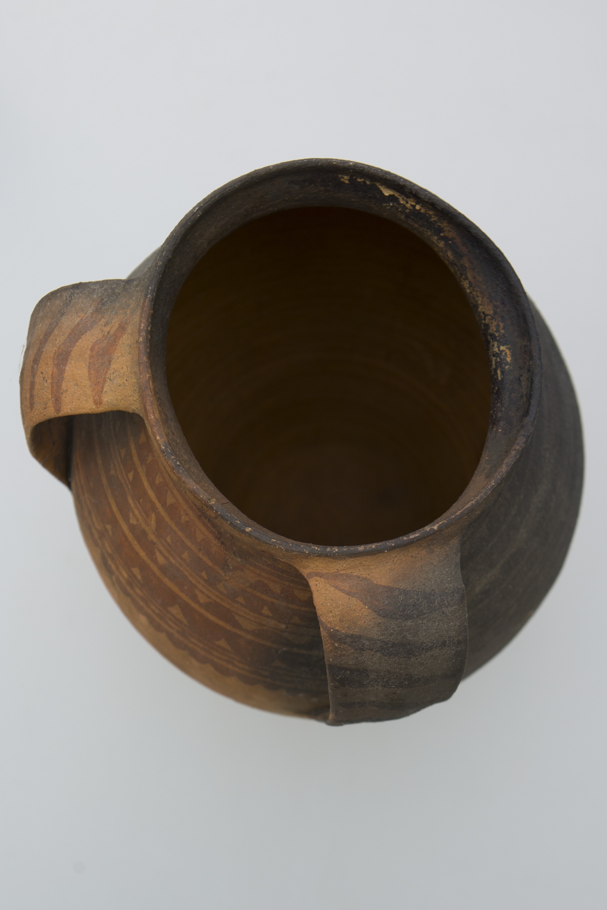 Vas ceramic de formă ovoidală pe bază inelară puțin înălțată; buza evazată; două toarte late apropiate, decoarte cu dungi oblice dispuse pe lungime. Decor: cercuri concentrice și motive meandrice intercalate. Fond:cărămiziu; cromatică: maro; jumătate din vas este afumat; (decorul este distrus).