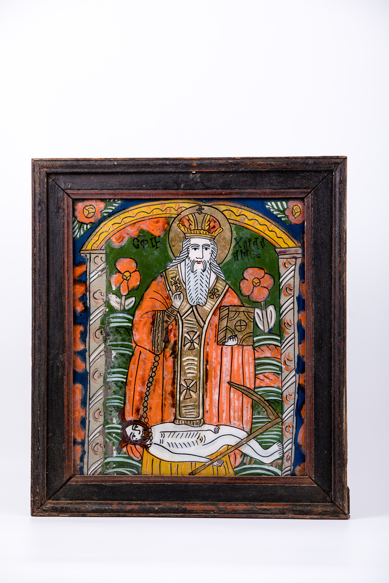 Sfântul Mare Mucenic Haralambie, făcător-de-minuni, este cel mai bătrân mucenic din cei prăznuiți de creștini. Este cunoscut ca și făcător-de-minuni, vindecător de boli și ocrotitor al caselor familiilor creștine. Central este pictat Sfântul, îmbrăcat cu veșminte liturgice, arhierești, cu sacos galben felon roșu vermillon și epitrahil brun-bronziu, cu patru cruci albe graffiate, cu mithră și aureolă. Fiind foarte bătrân, are barbă albă, lungă. În mâna stângă are Sfânta Evanghelie închisă și cu mâna dreaptă ține în lanț ciuma, reprezentată antropomorfic și Binecuvântează. Ciuma, simbolizând boala incurabilă și moartea, are secera în mână și coarne de diavol, fiind, totodată și păcatul, patima, aducătoare de moartea duhovnicească. În registrul superior, în dreapta și în stânga sfântului ierarh, sunt două flori, care reprezintă metaforic pe Sfinții Arhangheli Mihail și Gavriil. În registrul inferior, este un câmp de o alternanță cromatică verde-roșu cu striații albe, iar în registrul superior este cerul albastru cobalt cu ruje roșii - elemente florale stilizate, astfel creându-se o simetrie compozițională. Întreaga narațiune iconografică este încadrată de un chenar geometric arhitectural și floral. Două coloane și o arcadă de boltă sugerează Biserica. Cromatica este armonioasă: albastru cobalt, roșu vermillon, galben, ocru, verde spanac-avocado, alb, negru. Armonia cromatică se întrepătrunde estetic cu detaliile minuțioase ale desenului. Icoana este de Țara Oltului. Inscripția din româno-chirilică se traduce Sfântul Haralambie.