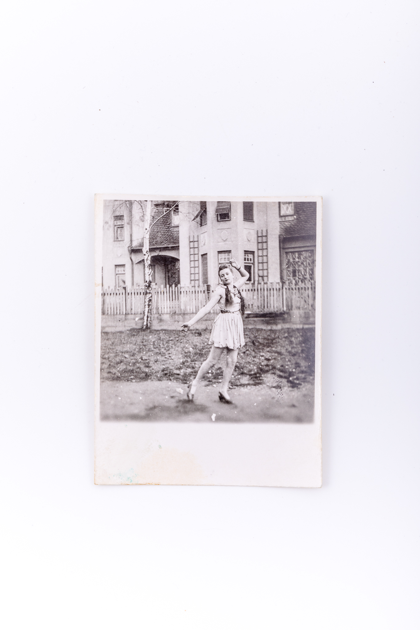 Fotografie de exterior realizată în fața unei clădiri din cărămidă. Hârtia fotografică este sensibilizată cu gelatino-bromură de argint de argint, prin D.O.P. (developing-out paper – imprimare prin developare). Prezintă o tânără în costum orășenesc. Se remarca postura artistică a tinerei. Pe verso însemnare manuscrisă cu culoare albastră: „30.11.1940”; lipit număr inventar 3029 CL, Turnișor.