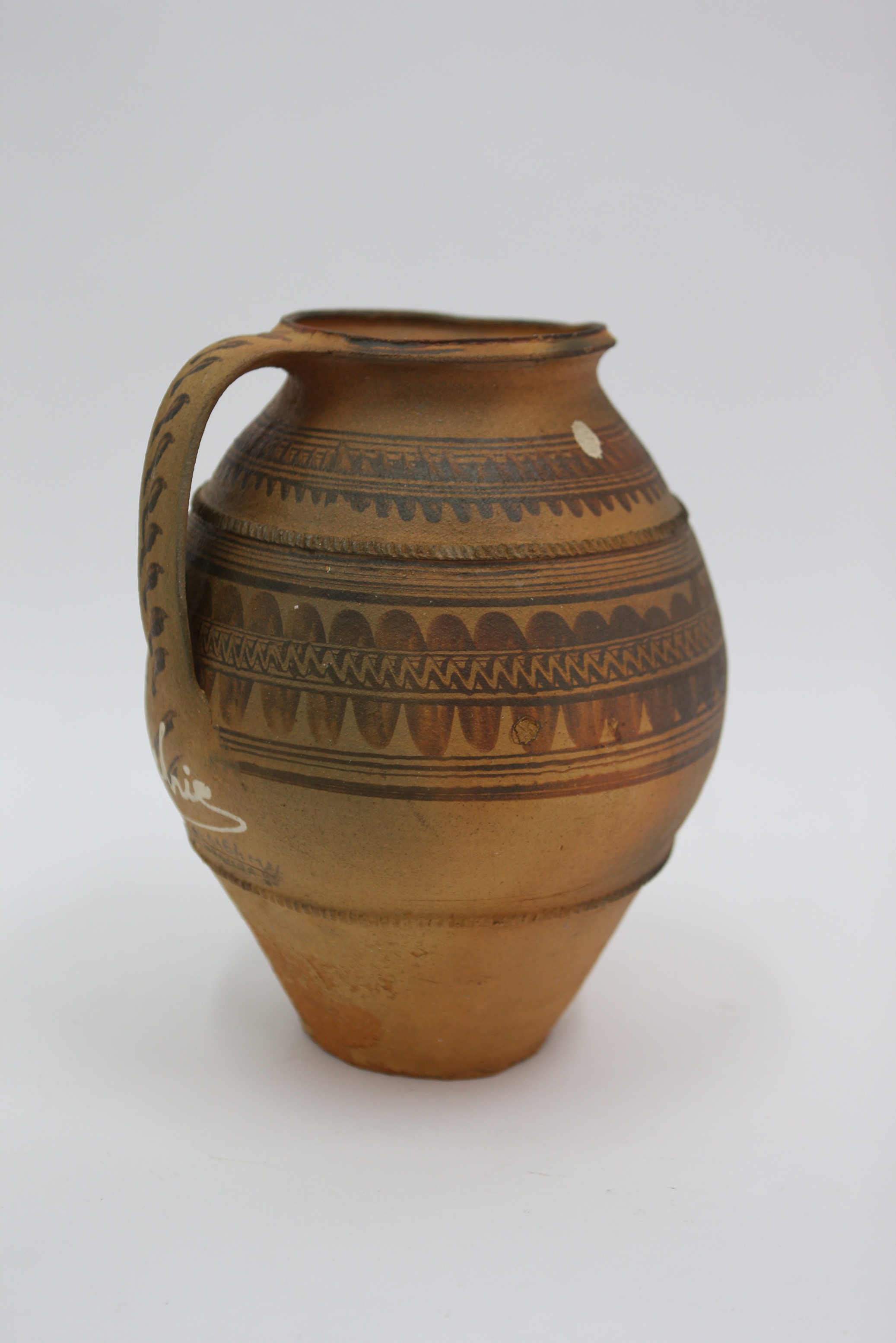 Vas ceramic de formă ușor tronconică, cu două toarte late alăturate și afrontate. Toartele pleacă imediat de sub gât; gura înălțată este evazată, apoi ușor invazată; vasul nu prezintă gât. Baza vasului este îngustată și pereții sunt vizibil evazați, zona mediană a vasului fiind bombată. Oala este decorată în jumătatea superioară cu motive geometrice formate din benzi de linii și linii în val; de asemenea, este decorată cu două brâuri alveolate; pe toarte se identifică decor cu linii în val; sub toarte se identifică inscripția Cătălina A. Mischie; cromatica: fond cărămiziu și gri, maro, negru