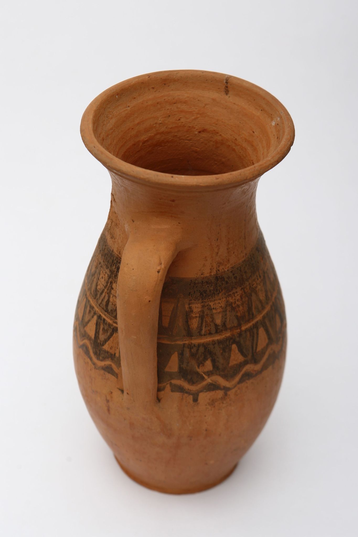Vas ceramic nesmălțuit de formă sferoidală, cu gâtul înalt, ușor evazat și buza rotunjită și răsfrântă. Prevăzut cu o toartă lată care pleacă din gât și se termină în zona inferioară. Decorat în partea mediană cu motive zoomorfe (dintele de lup), dispuse în două rânduri, separate de o linie circulară. În partea inferioară, este pictată o linie ondulată. Decorul este pictat cu degetul, cu humă neagră. Pe toată suprafața, recipientul este ușor șlefuit cu piatra. Cromatică: fundal: cărămiziu; motive: negru.