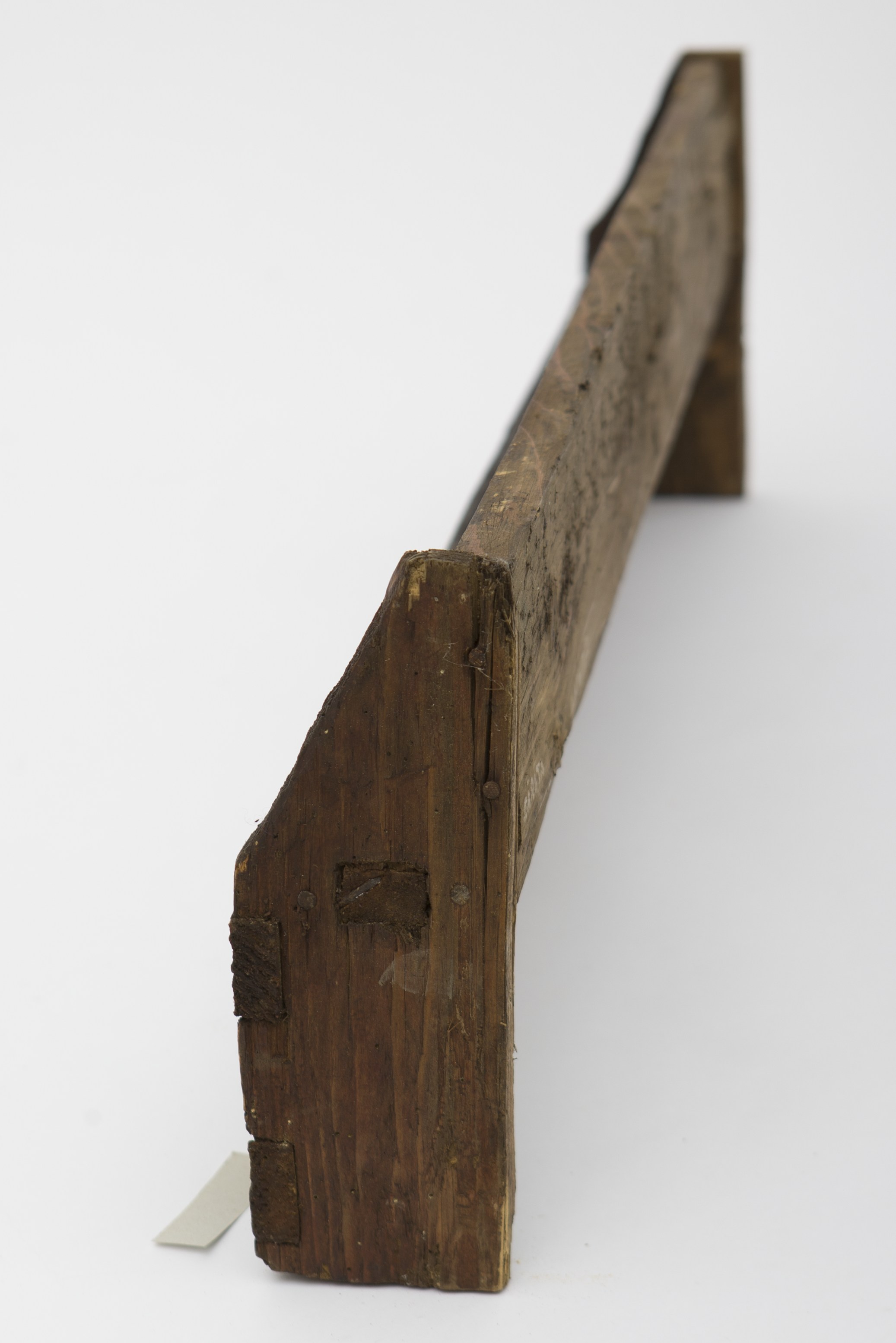 Piesă de mobilier de mici dimensiuni, realizată din lemn de brad și metal. Cuierul este format din două scânduri, fixate în formă de „L”, care prezintă la capete la capete alte două scânduri, reduse la dimeniuni, pentru întărire. Poliței i-au fost atașate frontal alte două scânduri încrustate. Decorul geometrizant simplist este format din încrustările în zig-zag, dispuse frontal. Cuierul era folosit în gospodărie pentru poziționarea vaselor ornamentale. Prezintă uzură funcțională. Cromatică: maro închis; culoarea patinată a lemnului.