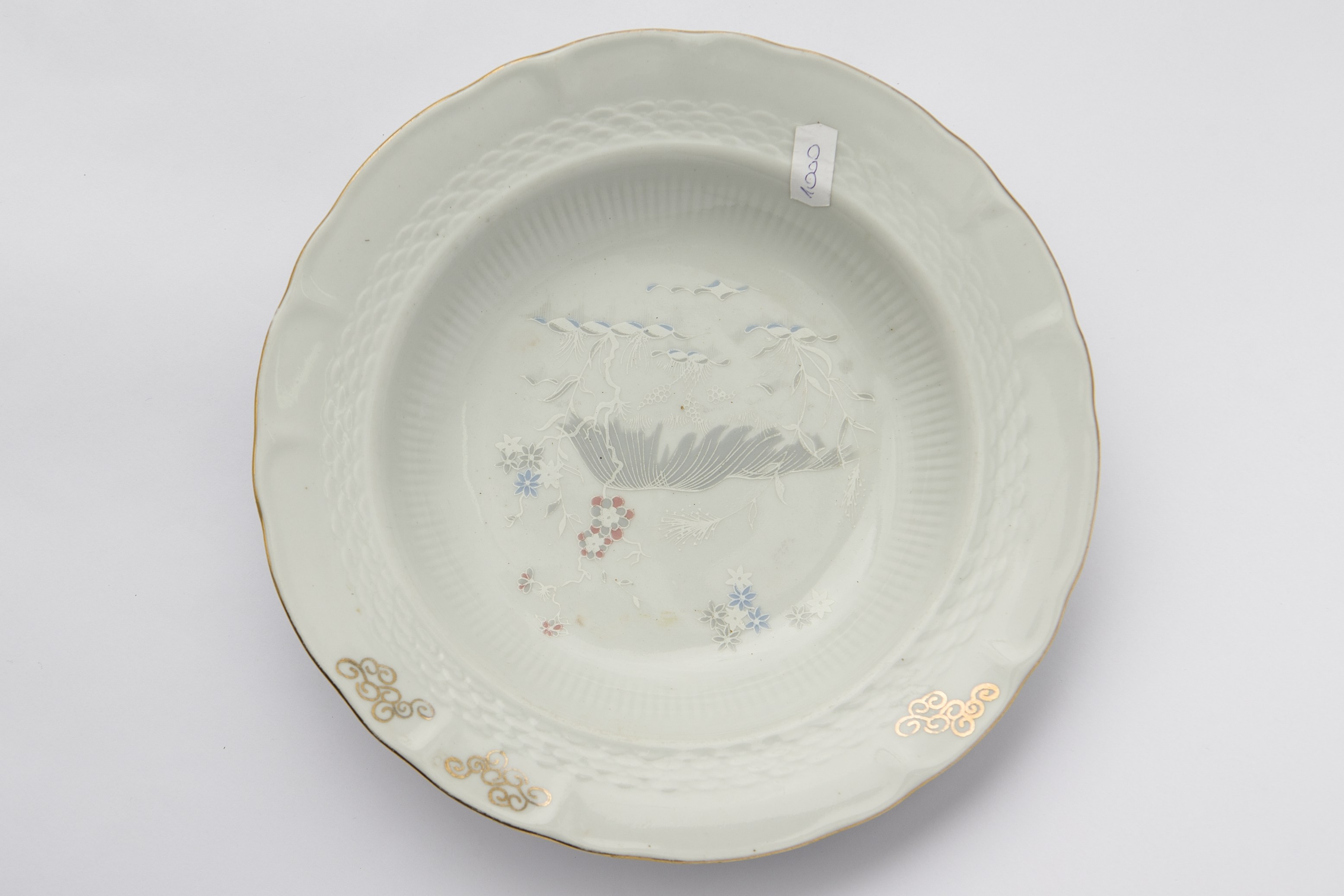 Vas ceramic de formă tronconică. Buza vălurită este conturată (exterior) cu auriu. În imediata apropiere a buzei sunt motive florale de culoare aurie cât și motive florale și geometrice ștanțațe. În zona centrală motive florale multicolore. La posterior ștampilat ”Cluj Made in Romania''. Cromatică: fond: gri; motive: auriu; alb; maro; gri; albastru.