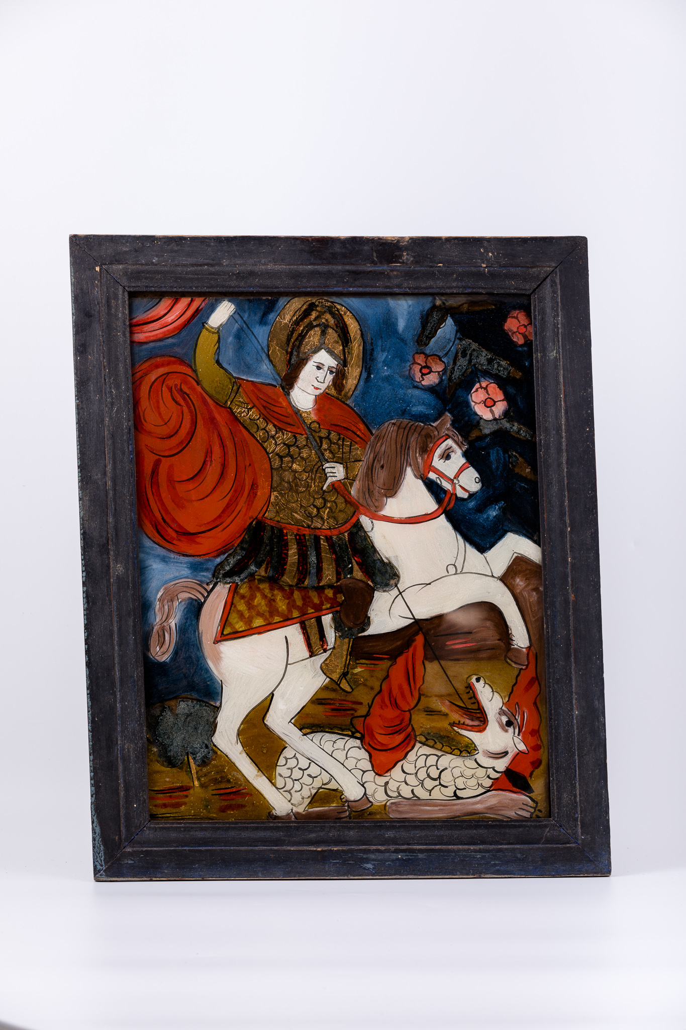 Sfântul Mare Mucenic Gheorghe este așezat călare pe un cal alb cu șa galbenă-ocru cu romburi orange, omorând balaurul alb-crem-brun cu creastă roșie-acajou, solzi și coadă lungă, cu lancea, pe care o ține cu amândouă mâinile, înfingându-i-o animalului în gâtlej. Fondul este cerul albastru ultramarin bleumarin în registrul superior. În registrul inferior, fondul este brun-ocru și albastru cobalt, cu linii ondulatorii verzi, cele două registre în centrul icoanei ușor întrepătrundu-se. Mantia Sfântulu Mucenic Purtător de Biruință este roșie-vișinie stacojie, având cămașa de cavaler cu zale. Culoarea roșie este caracteristică mucenicilor și martirilor. Cerul albastru este acoperit cu elemente fitomorfe - flori de măr roz-roșii. Icoana, fiind din Mărginimea Sibiului, are desenul mai neglijent, cromatica puternică, fauvistă. Cromatica este armonioasă: roșu vermillon-stacojiu, albastru ultramarin bleumarin, roz, brun, galben-ocru, gri, alb, negru.