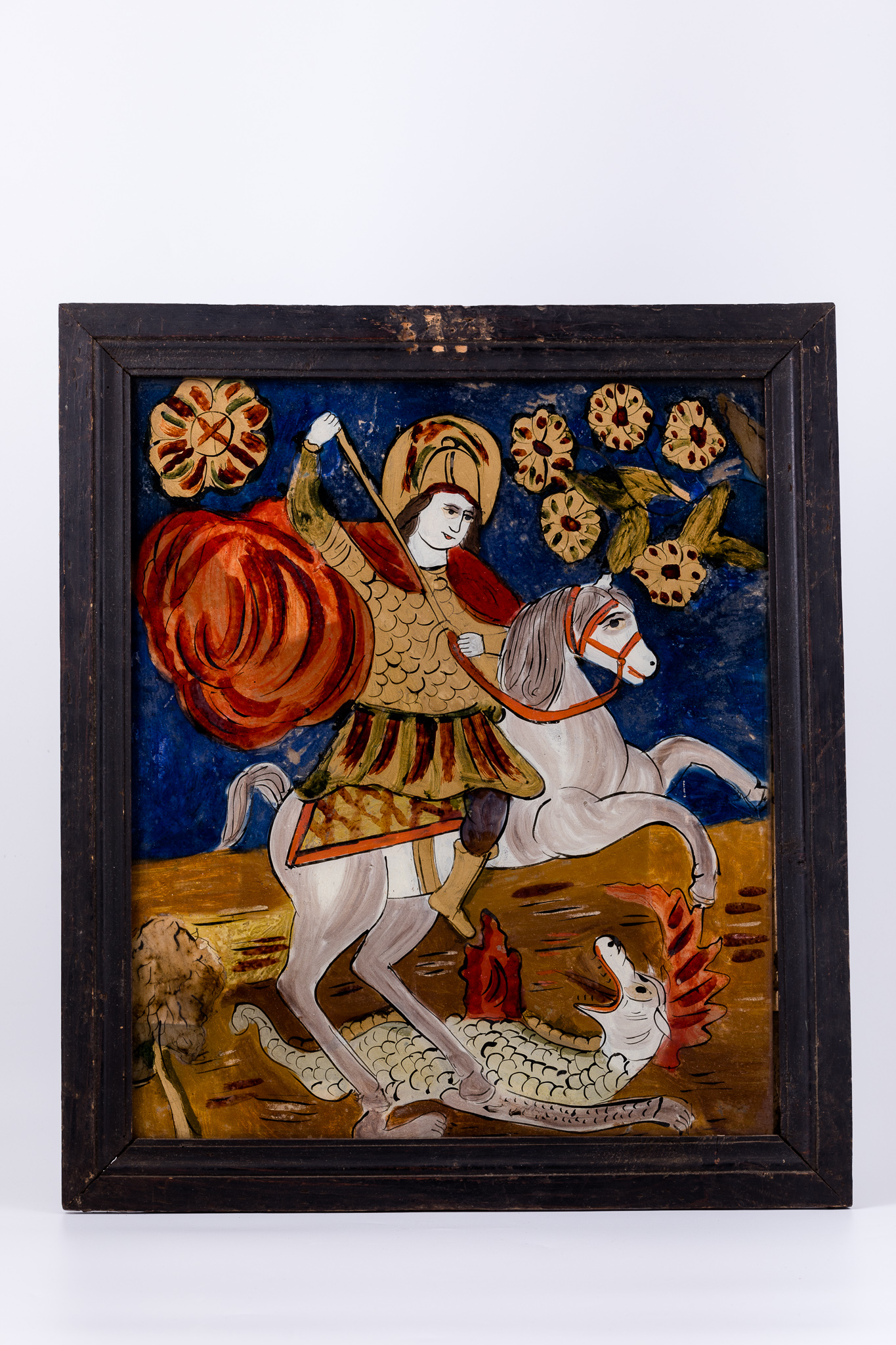 Sfântul Mare Mucenic Gheorghe este așezat călare pe un cal alb cu șa galbenă-ocru-orange, omorând balaurul alb-gri cu creastă roșie, solzi și coadă lungă, cu lancea, pe care o ține cu amândouă mâinile, înfingându-i-o animalului în gâtlej. Fondul este cerul albastru, cobalt în registrul superior. În registrul inferior, fondul este brun-sierra arsă, cu linii ondulatorii albe-negre, cele două registre în centrul icoanei ușor întrepătrundu-se. Mantia Sfântului Mucenic Purtător de Biruință este roșie, având cămașa de cavaler cu zale. Culoarea roșie este caracteristică mucenicilor și martirilor. Cerul albastru este acoperit cu elemente fitomorfe - flori ocru-roșii. Icoana, fiind din Mărginimea Sibiului, are desenul mai neglijent, cromatica vie puternică, fauvistă. Cromatica este armonioasă: roșu vermillon-stacojiu, albastru-cobalt, verde kaki și văratic, galben-ocru, gri, alb, negru.
