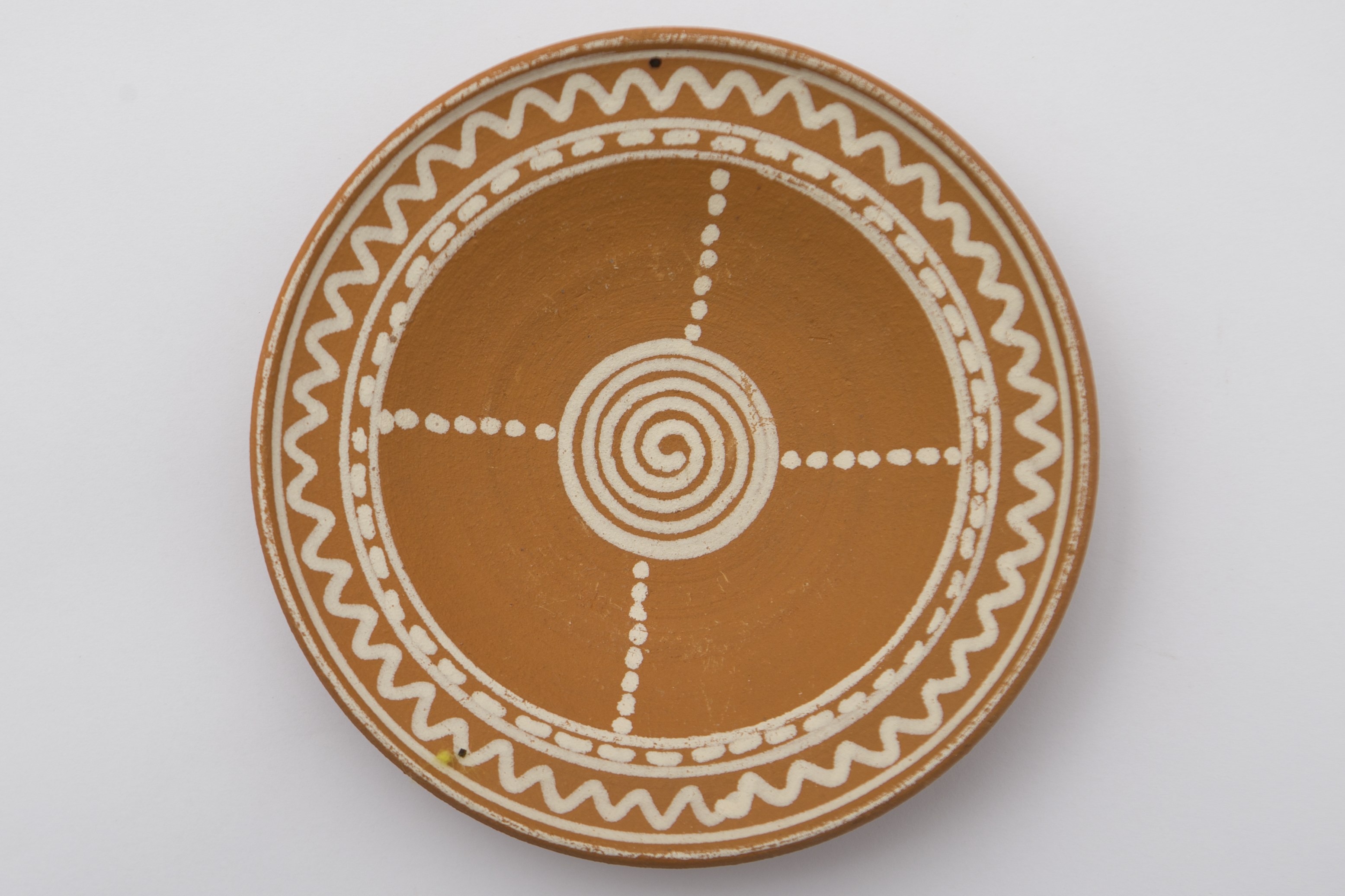 Vas ceramic cu fundul plat puțin adâncit și marginile evazate, puțin ridicate. Pe fundul vasului a fost pictată cu angobă albă o spirală. De pe ea urcă pe pereții vasului patru raze punctate. Marginea a fost împărțită în două benzi: una punctată, a doua vălurită. La posterior ștanțat ”D. ȘCHIOPU C. VLĂDEȘTI 1979'' înscris într-un cerc. Cromatică: fond: cărămiziu; motive: alb.