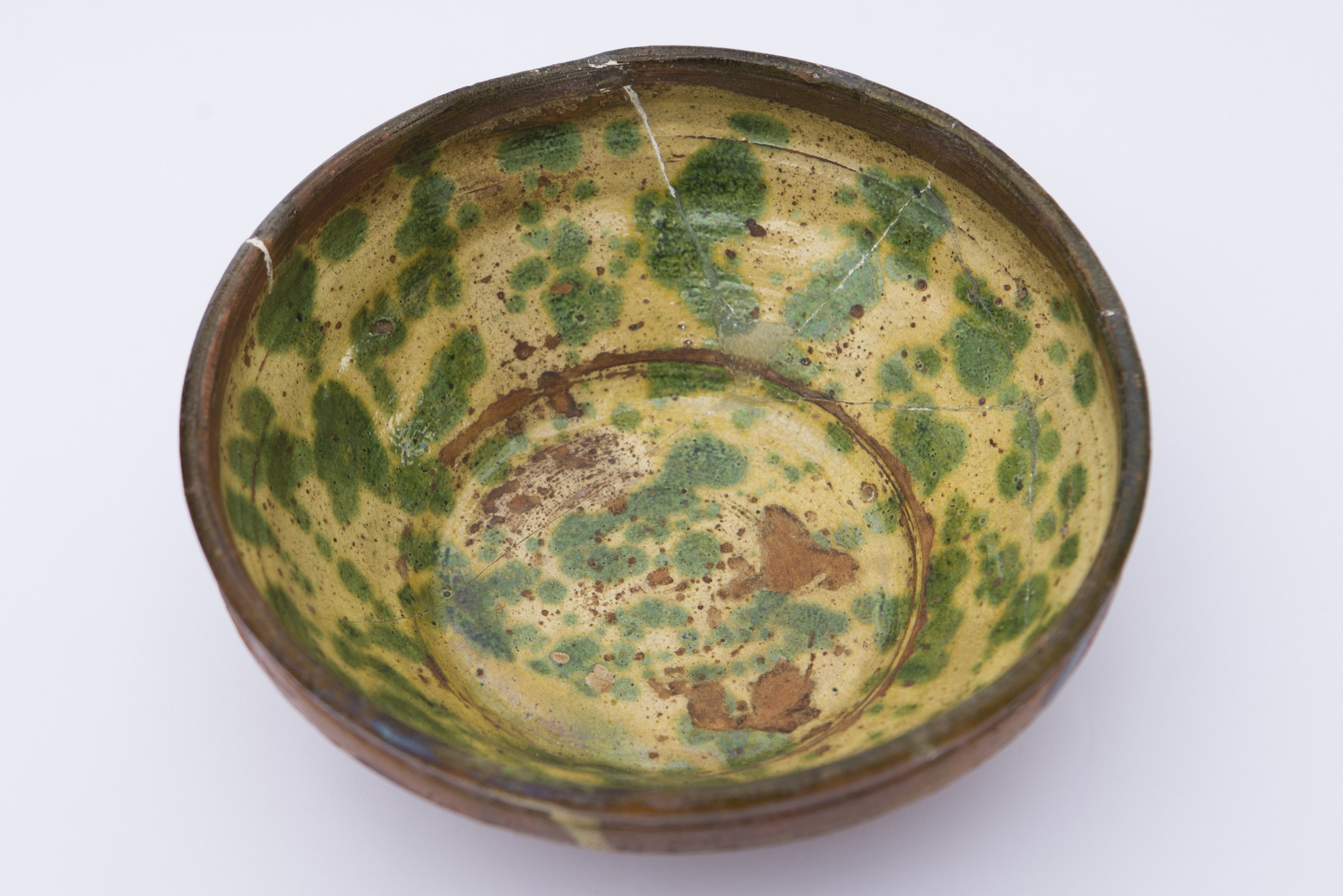 Vas ceramic de formă tronconică, are pereții înalți, puțin evazați, cu buza verticală răsfrântă spre interior. Pe un fond galben-crem de smalț s-a stropit cu culoare verde. Pe partea posterioară prezintă două găuri prin care trece ața pentru agățat. Cromatică: fond: crem-gălbui; motive: maro; verde.