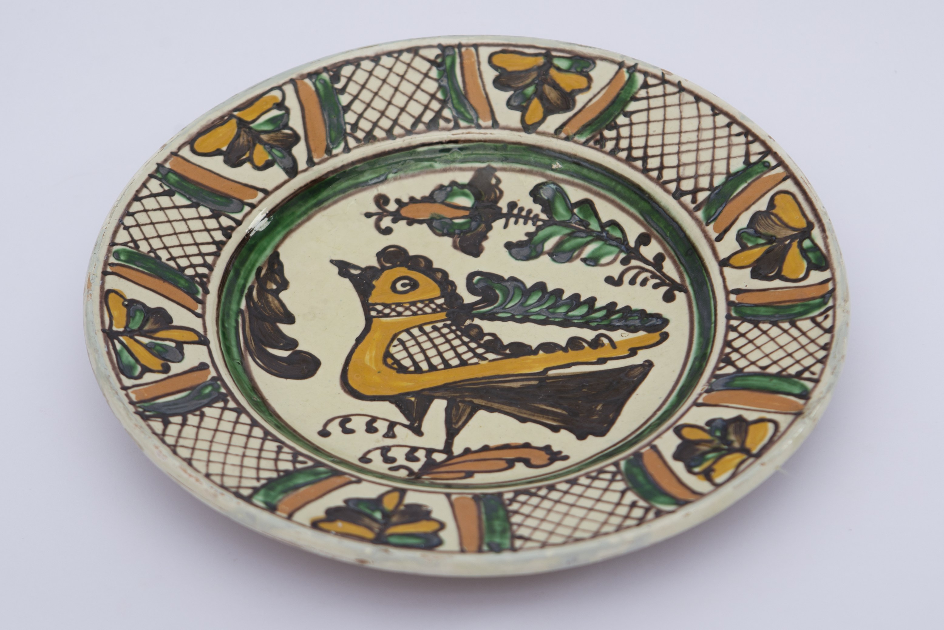 Vas ceramic de formă tronconică aplatizată, pe bază inelară. Decor amplasat pe toată suprafața; ordonat in registre ilustrând motive geometrice propriu-zise: linia dreaptă, cercul; motive fitomorfe: frunza; motive florale: lalea. Pe fundul vasului dispusă o pasăre, înscrisă într-un cerc verde. Pe marginile farfuriei dispuse șase grupuri de frunze grupate aproximativ triunghiular, încadrate de câte două dungi verticale portocalii și verzi conturate cu maron, spațiul liber fiind hașurat cu întretăieri de linii diagonale. Baza inelară perforată în vederea atârnării vasului. La posterior, pe fund, inscripționat cu negru ”Iosza Ianos Korond 1974''. Cromatică: fond: alb; motive: verde; brun; portocaliu; galben; maro.