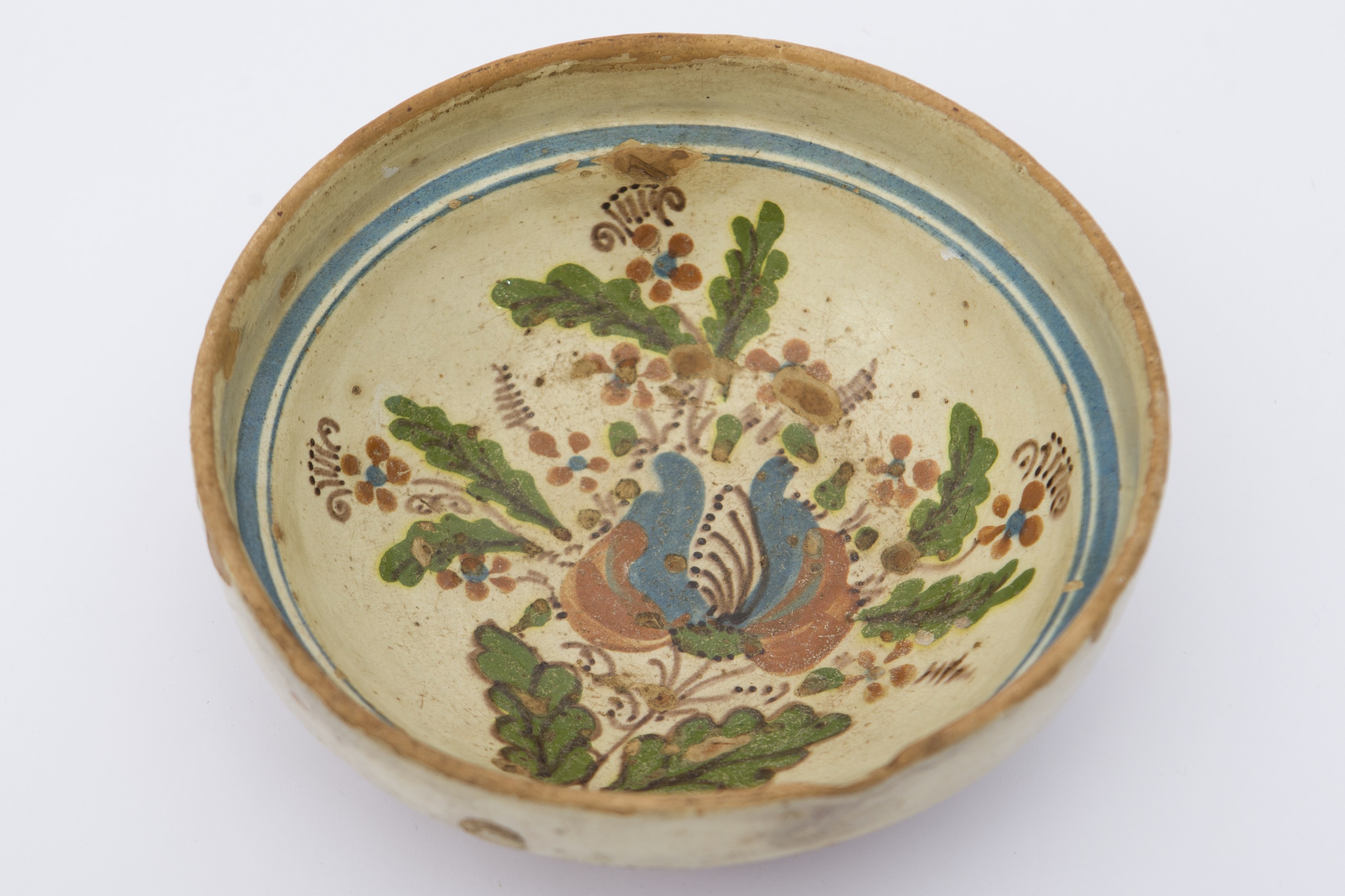 Piesă ceramică smălțuită în interior, de formă tronconică, cu baza plată, pereții ridicați și marginea evazată. Pe fond alb decorații realizate prin pictare cu pensula, în interiorul vasului, în registru fitomorf. În culorile maro și albastru se ilustrează flori de diferite dimensiuni în alternanță cu frunze verzi și linii maro. Întreg aranjamentul este mărginit de motive geometrizante: două linii circulare drepte, de culoare albastră. Blidul era folosit pentru servirea hranei. Prezintă uzură funcțională. Cromatică: fond: cărămiziu (exterior); alb (interior); motive: verde; albastru; maro roșcat.