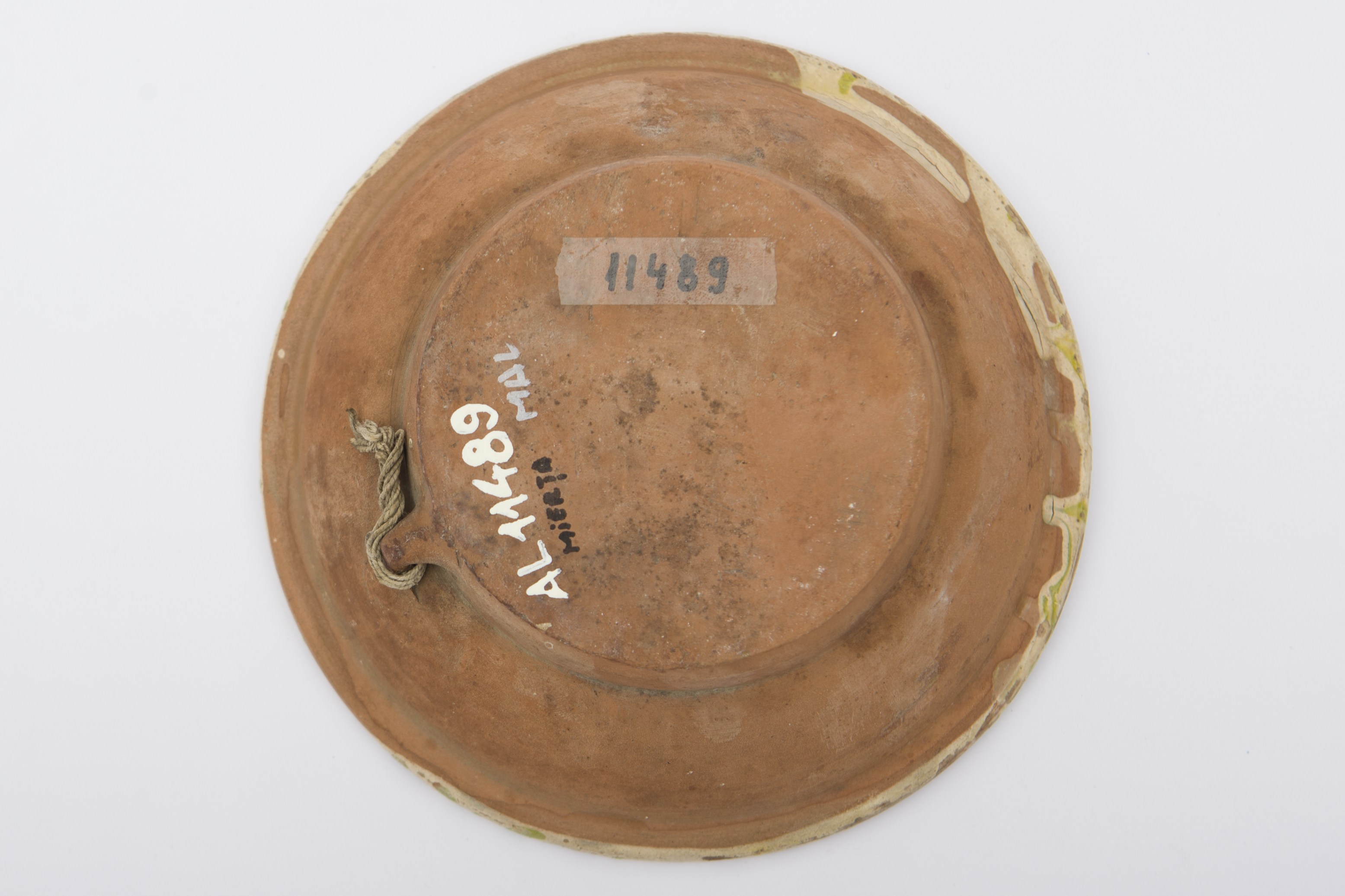 Recipient ceramic smălțuit în interior, de formă tronconică: fundul plat; pereții ușor ridicați și buza evazată. Pe fond crem, decorații realizate cu prin stropire în culoarea galben-verzui, pe toată suprafața interioară. Pereții interiori conturați de două linii circulare incizate și vopsite în culoare albastră. Pe spate prezintă o tortiță de mici dimensiuni pentru suspendare pe perete. Blidul era folosit pentru servirea hranei. Prezintă uzură funcțională. Cromatică: fond: cărămiziu (exterior); crem (interior); motive: galben-verzui; albastru.