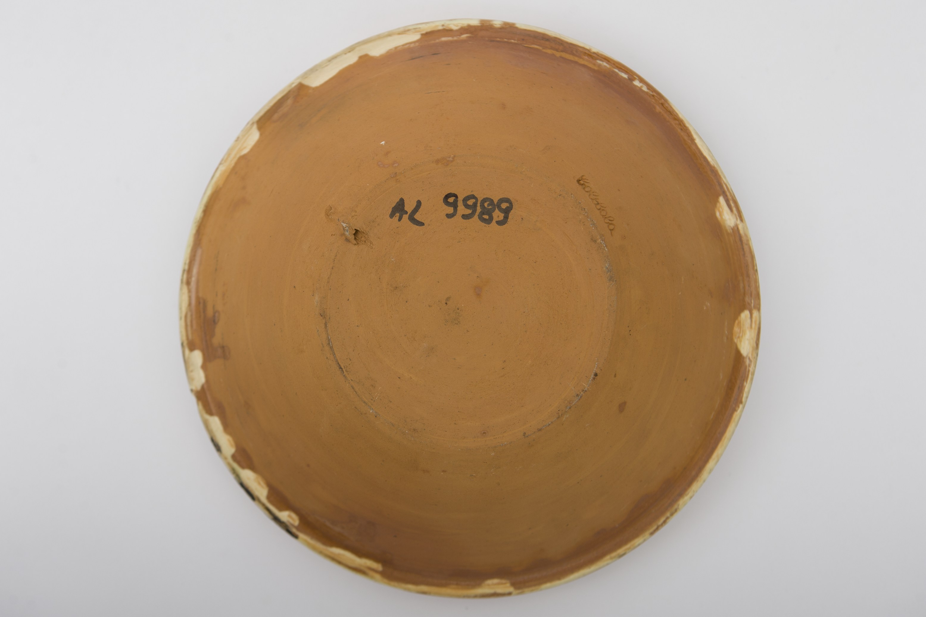 Vas ceramic smălțuit de formă rotundă și profil tronconic aplatizat cu marginile larg evazate. Decorul este fin incizat, în tehnica sgrafitării, înainte de pictare. Pe fundul vasului este amplasat motivul vasului cu flori, ilustrând o floare dispusă vertical pe o tulpină lungă cu trei rânduri de flori, încadrată de alte două motive florale, sugerate de cerc puncriform, arc de cerc și registru de linii hașurate (floarea soarelui) și doi sori de mici dimensiuni în partea superioară. Pe pereții farfuriei, între linii concentrice, este prevăzută cu un motiv geometric-floral stilizat (arc de cerc, linii drepte și ondulate). La posterior, baza este perforată pentru atârnare și deasupra bazei regăsim incizată inscripția ,,Colibaba''. Cromatica: fond: alb; motive: verde, galben, brun.