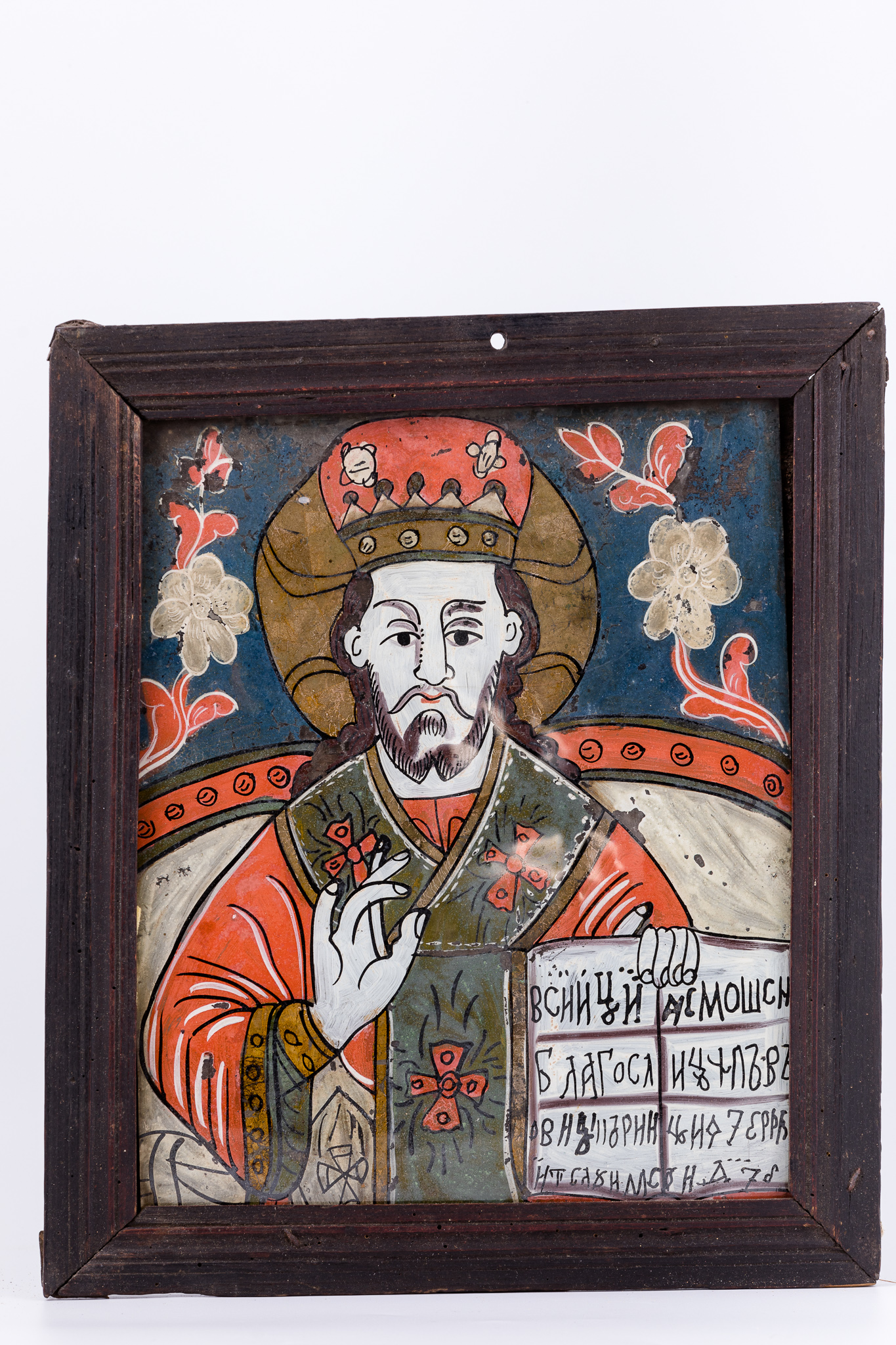Sfântul Mare Ierarh Nicolae, făcător de minuni, îmbrăcat în veșminte liturgice, de ierarh, sacos și felon roșu vermillon-stacojiu, cu interiorul vernil-gri și epitrahil-patrafir verde-gri-kaki, cu trei cruci roșii brodate. Ține în mâna stângă Sfânta Evanghelie deschisă și cu mâna dreaptă Binecuvântează. Este unul dintre cei mai populari și iubiți sfinți, ocrotitor al caselor, familiilor și copiilor. Are mithră arhierească și aureolă. Fondul este cerul albastru cobalt-regal, în registrul superior și vernil-absint cu mandorle de nouri albi, în registrul inferior. Tronul arhieresc este bogat ornamentat cu elemente decorative bronzii și tronul arhieresc gri-marmoreic, cu butoni roșii. Desenul este fin conturat. În registrul superior, ancadrator, asemenea unei arcade-bolți, sunt dispuși doi trandafiri roșii-tranfafirii, cu ramură din ghirlandă. Cromatica este armonioasă și distinsă: roșu vermillon-stacojiu, albastru regal-cobalt, verde brad, kaki, verde-gri, bronz, brun, bej, crem, marmoreic, auriu, alb, negru. Icoana este din Nicula.