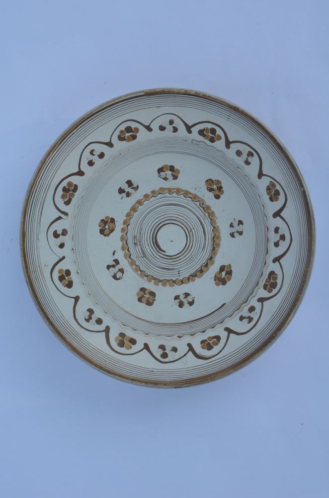 Recipient din lut de uz casnic, nesmălțuit, angobat, de formă circulară, cu profil tronconic, cu buza rotunjită. Pe pereții interiori,vasul este decorat cu cornul, cu motive geometrice și florale. În centrul vasului este pictată o spirală încadrată de un șir de puncte. Ornamentația continuă cu nouă flori bicolore stilizate, distanțate, și două registre de linii concentrice subțiri despărție de un șir de flori inserate într- un contur de floare. Cromatică: fundal alb; motive: gri, maro închis, maro deschis.