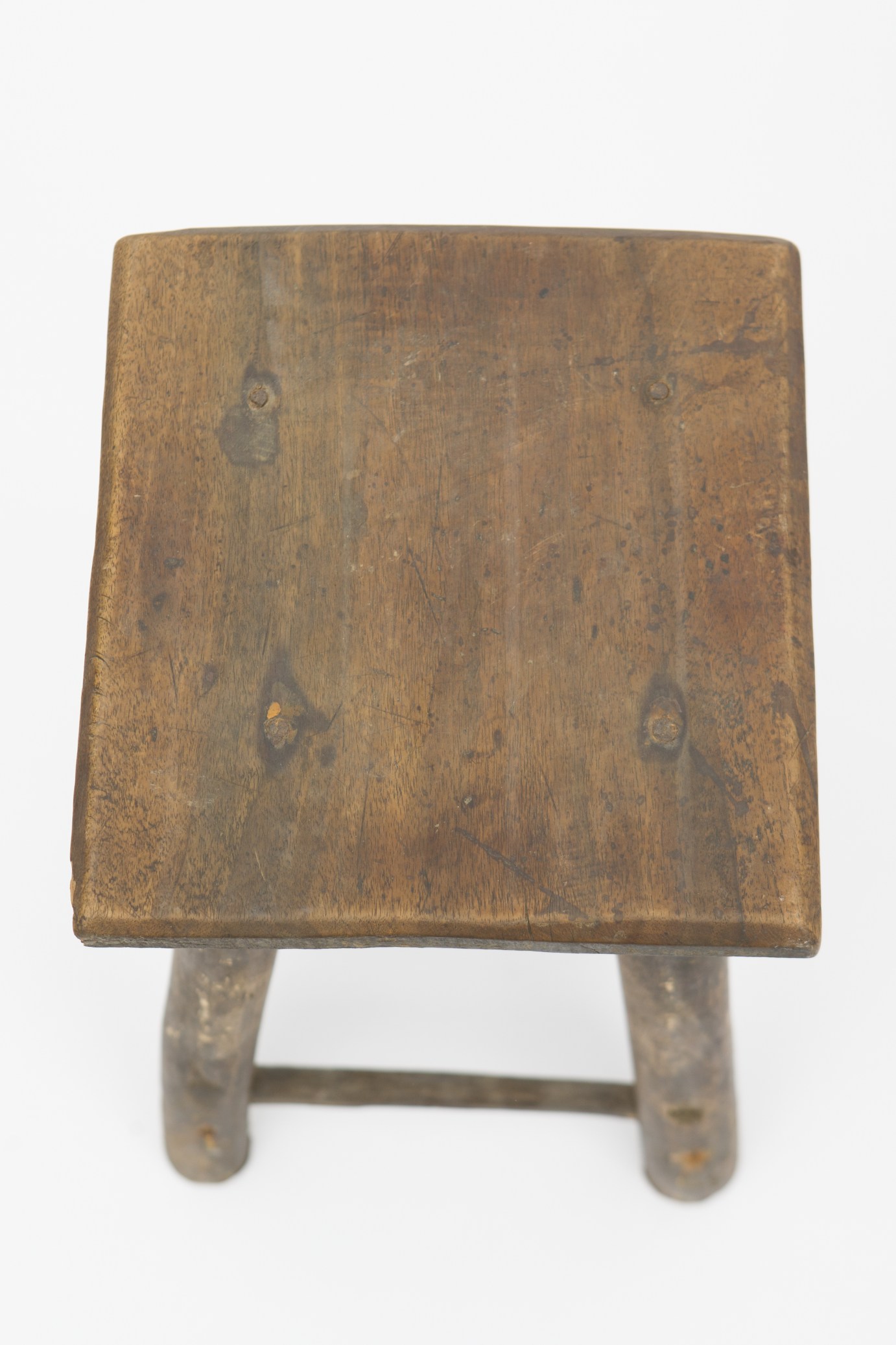 Obiect de mobilier de mici dimensiuni, realizat din metal și lemn de fag și brad. Scaunul este format din blatul patrulater, susținut de cele patru picioare cilindrice, ușor evazate în partea inferioară. În imediata apropiere a blatului, piesa a fost întărită de patru stinghii din lemn, dispuse orizontal. Alte patru stinghii, consolidează piesa în proximitatea bazei. Nu prezintă decor. Scaunul era folosit pentru mobilarea interioarelor. Prezintă uzură funcțională. Cromatică: culoarea patinată a lemnului.