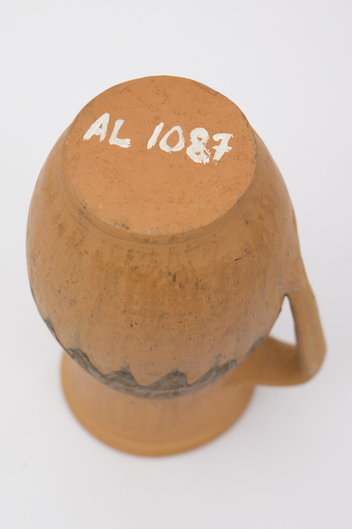 Vas ceramic nesmălțuit de formă sferoidală, cu gâtul înalt, ușor evazat și buza răsfrântă și dreaptă. Prevăzut cu o toartă care pleacă din gât și se termină în zona inferioară. Decorat în partea mediană cu motive zoomorfe (dintele de lup) , realizate cu cornul, în humă neagră.Sub buză, prezintă o linie subțire incizată, concentrică. Pe toată suprafața, recipientul este ușor șlefuit cu piatra. Cromatică: fundal: cărămiziu; motive: negru.