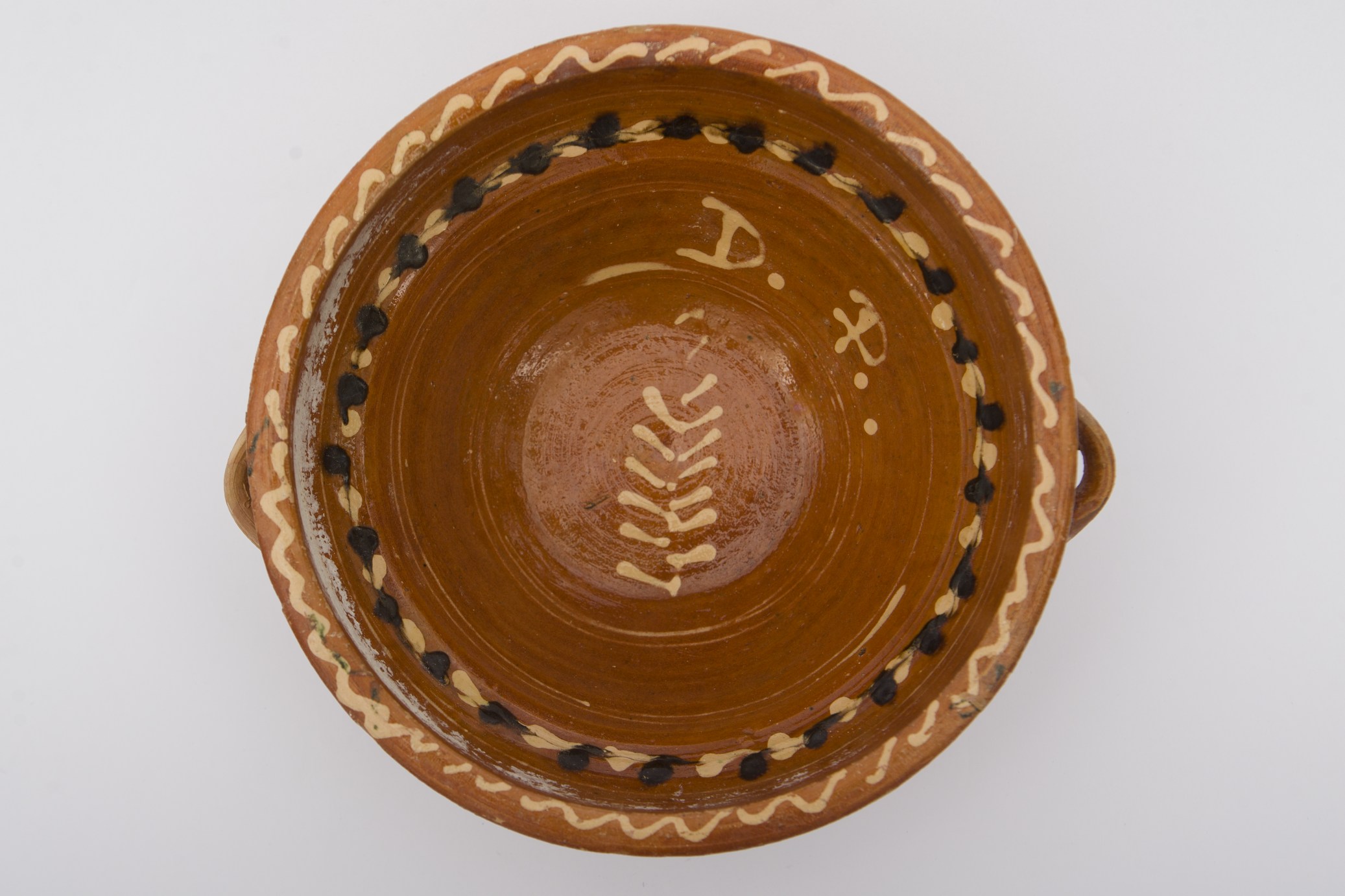 Vas ceramic, smălțuit în interior, de formă rotundă, profil tronconic și pereți evazați. Sub buză prezintă două tortițe laterale pentru manipulare. Pe fundul vasului amplasată o ,,crenguță de brad', sugerată de o linie dreaptă de unde se desprind lateral linii diagonale dispuse descrescător spre vârf, înscrisă într-un cerc concentric. Încă două asemenea cercuri fiind dispuse pe pereții interiori, împreună cu un șir micii lini albe și negre palmate dispuse circular. Buza dreaptă conturată cu o linie ondulată dispusă circular. Pe peretele interior, deasupra cercului care circumscri motivul central, pictate inițialelele ,,D.P''. Cromatica: fond: cărămiziu; motive: alb, negru.