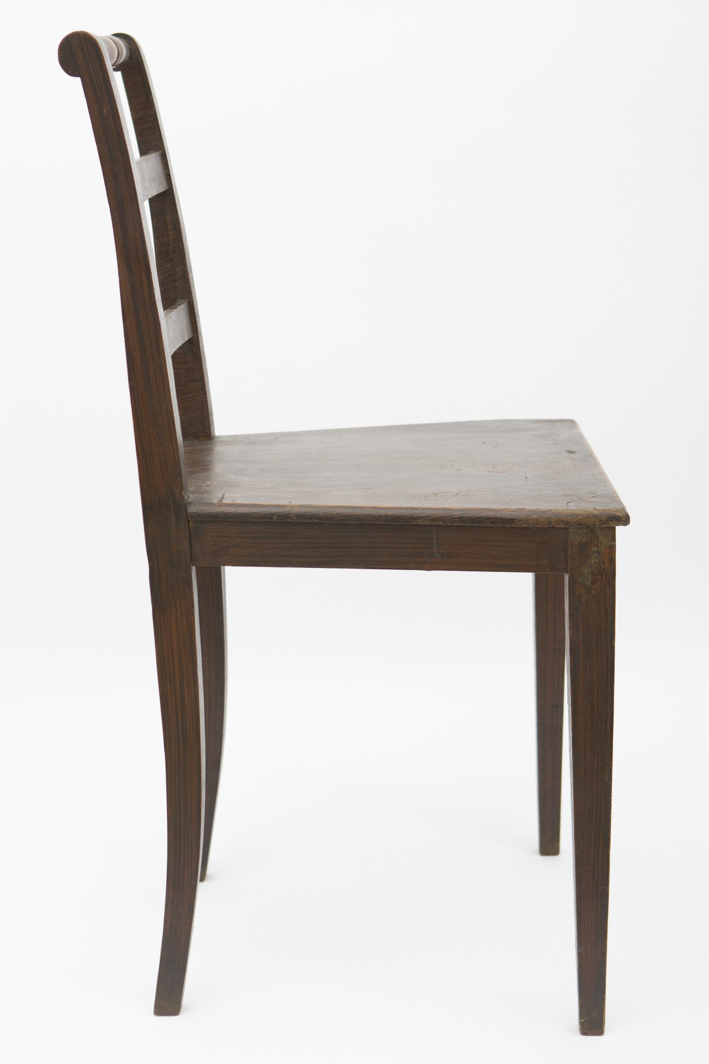 Piesă de mobilier de dimeniuni medii, realizată din lemn de brad și metal. Scaunul este format din blatul trapezoidal, susținut de cele patru picioare, prelucrate în patru fețe. Două dintre picioare, cele din spate, sunt mai lungi, formând astfel spătarul. Sub blat, patru stinghii, dispuse orizontal, consolidează piesa. Spătarul prezintă la rândul lui, alte trei stinghii orizontale. Stinghia superioară a fost ușor modelată prin strunjire. Scaunul era folosit în gospodărie pentru mobilarea interioarelor. Prezintă uzură funcțională. Cromatică: culoarea patinată a lemnului; culoarea patinată a metalului.
