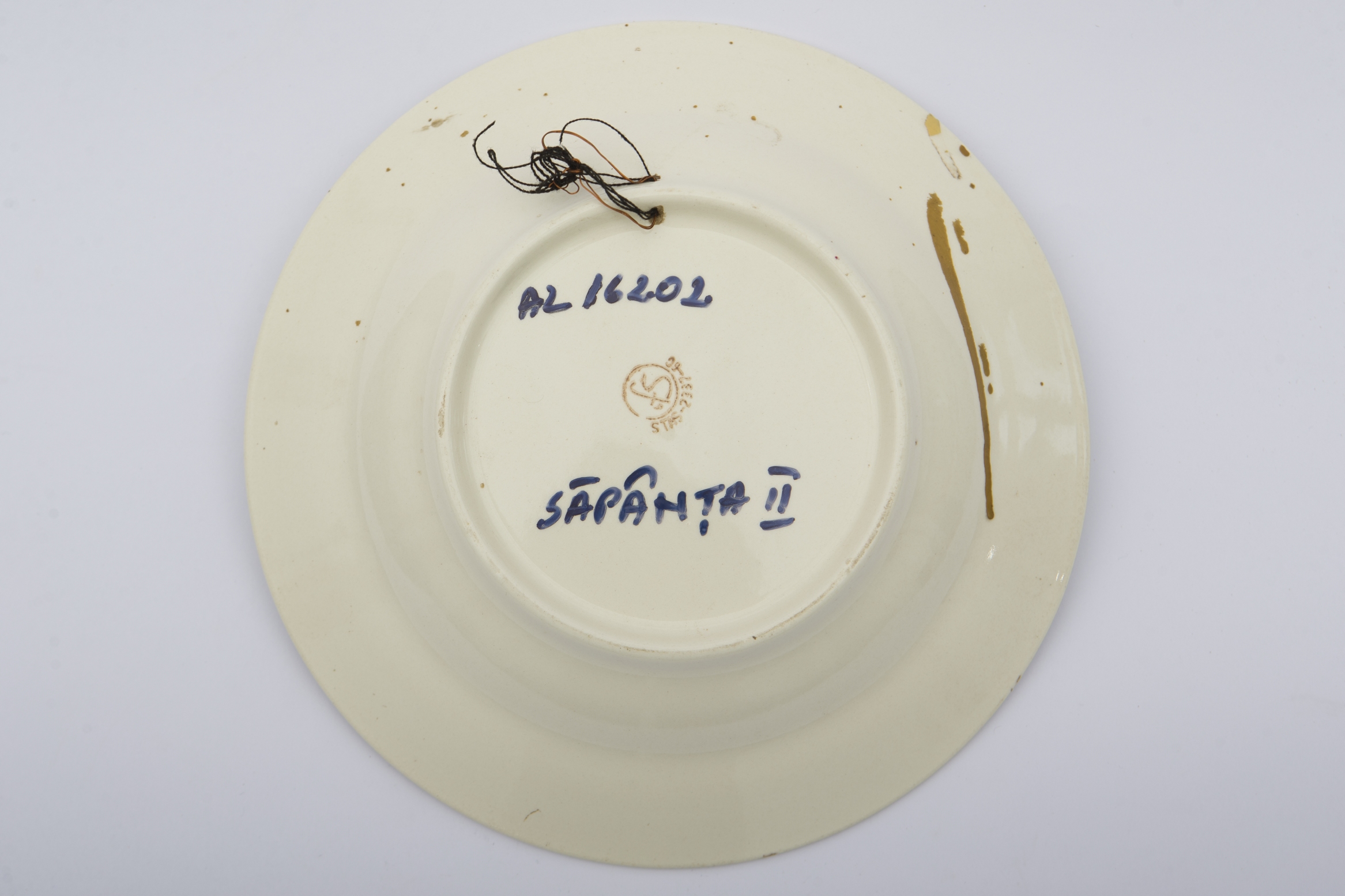 Recipient ceramic smălțuit, de formă circulară, cu baza plată susținută de un inel, pereții ușor ridicați și buza evazată. Peste stratul alb au fost realizate decorații fitomorfe, ilustrând cinci registre, compuse din flori policrome. Pe spate au fost săpate două orificii pentru fixarea pe perete sau blidar. Farfuria era folosită pentru servirea hranei sau decorarea interioarelor. Prezintă uzură funcțională. Cromatică: fond: alb; motive: roz; albastru; verde; galben.