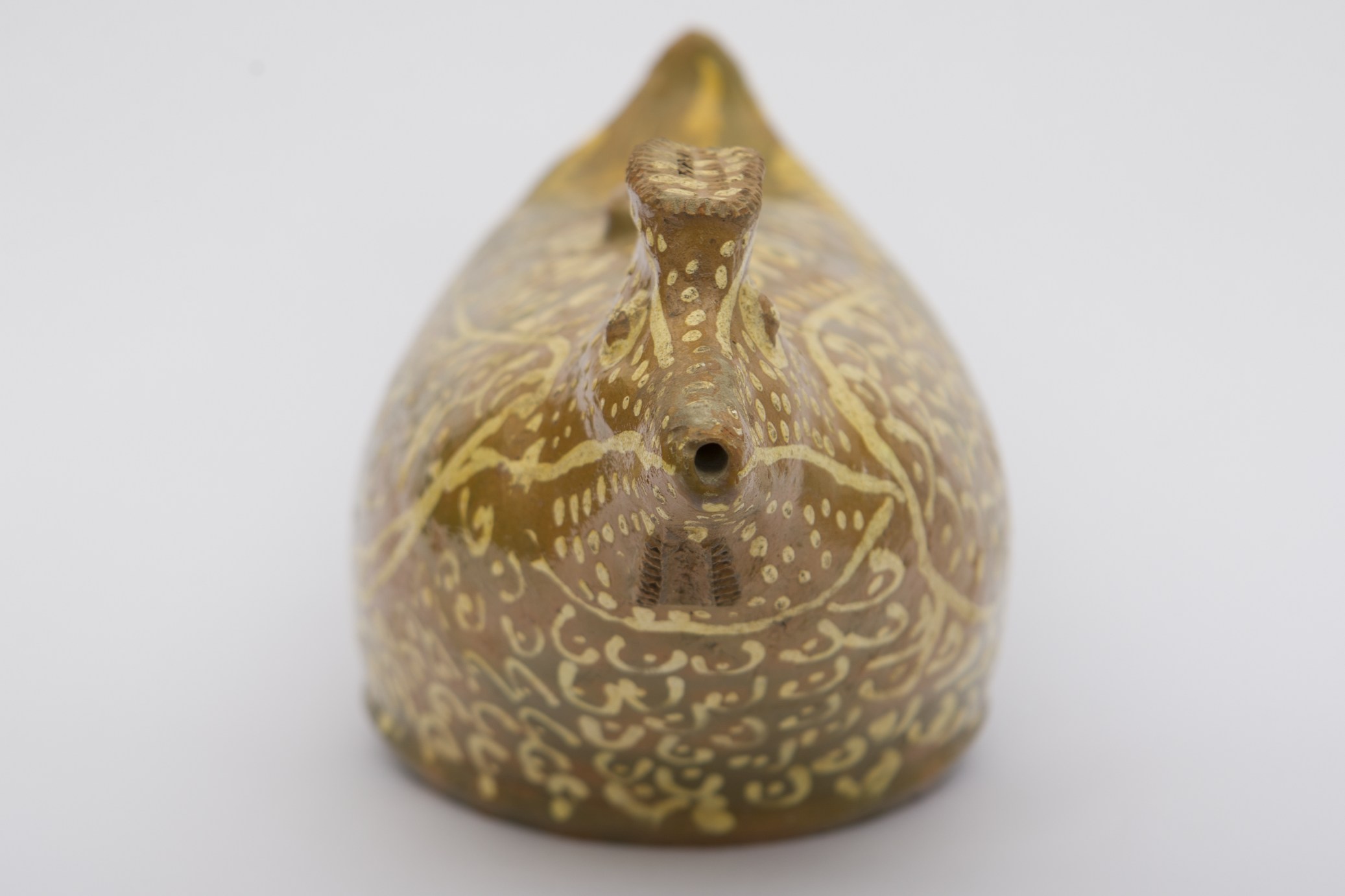 Vas ceramic de formă avimorfă reprezentând o pasăre stilizată (probabil o rață),cu corp bombat și baza circulară. Orificiul de umplere este amplasat pe spatele păsării, iar ciocul constituie orificiul prin care se scurge lichidul. Ornamente cu rotița executate sub cioc și pre creastă. Pe tot coprul vasului decor realizat prin pictare cu pensula compus din lini arcite cu câte un punct în mijloc, linii drepte și punctiforme sugerând penajul păsării. Pe partea superioară inscripționat cu pensula ,, Olar Ștefan Dingă'' și ,,Noroc să dia D.''. Cromatica: fond: maro; motive: vernil, alb.