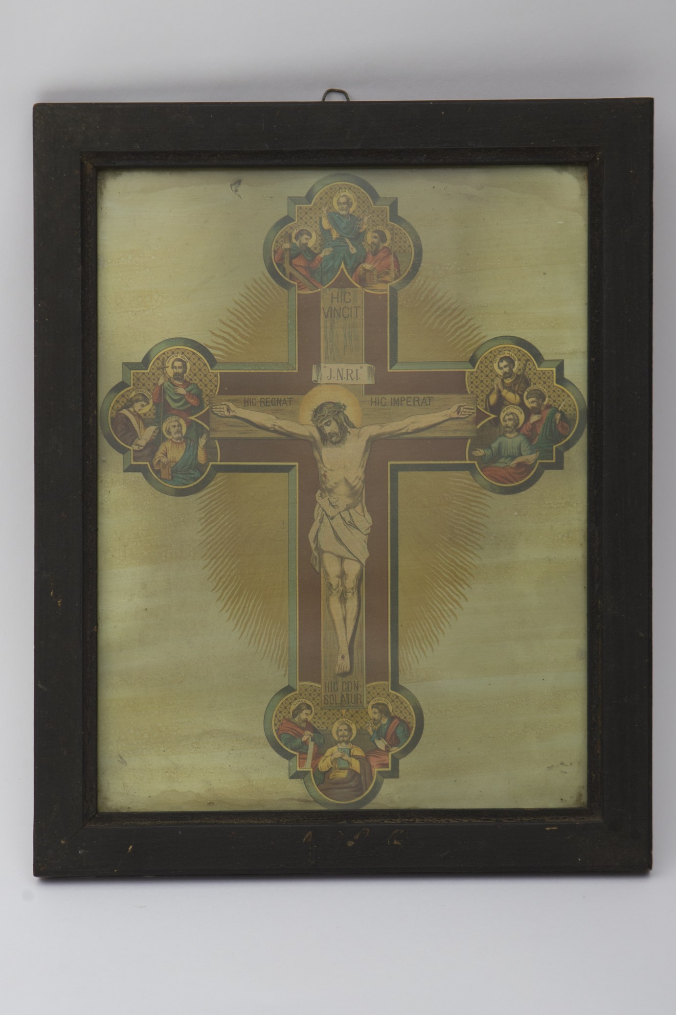 Litografie reprezentându-l pe Iisus răstignit, la extremitatea fiecărui braț al crucii, în interiorul unui trilob sunt grupați câte trei apostoli pe aura cărora este trecut numele în latină cu majuscule, inscripție în latină pe cruce, sus "HIC VINCIT", pe o eșarfă mai jos JNRI, deasupra brațului drept al lui Iisus "HIC REGNAT", iar deasupra celui stâng "HIC IMPERAT", sub picioare "HIC CONSOLATUR", ramă de lemn maro, în partea inferioară a ramei datarea 1929, în partea superioară are un inel pentru agățare, în spatele crucii un soare oval galben. Cromatică: maro, verde, galben, roșu, albastru, portocaliu, auriu, alb