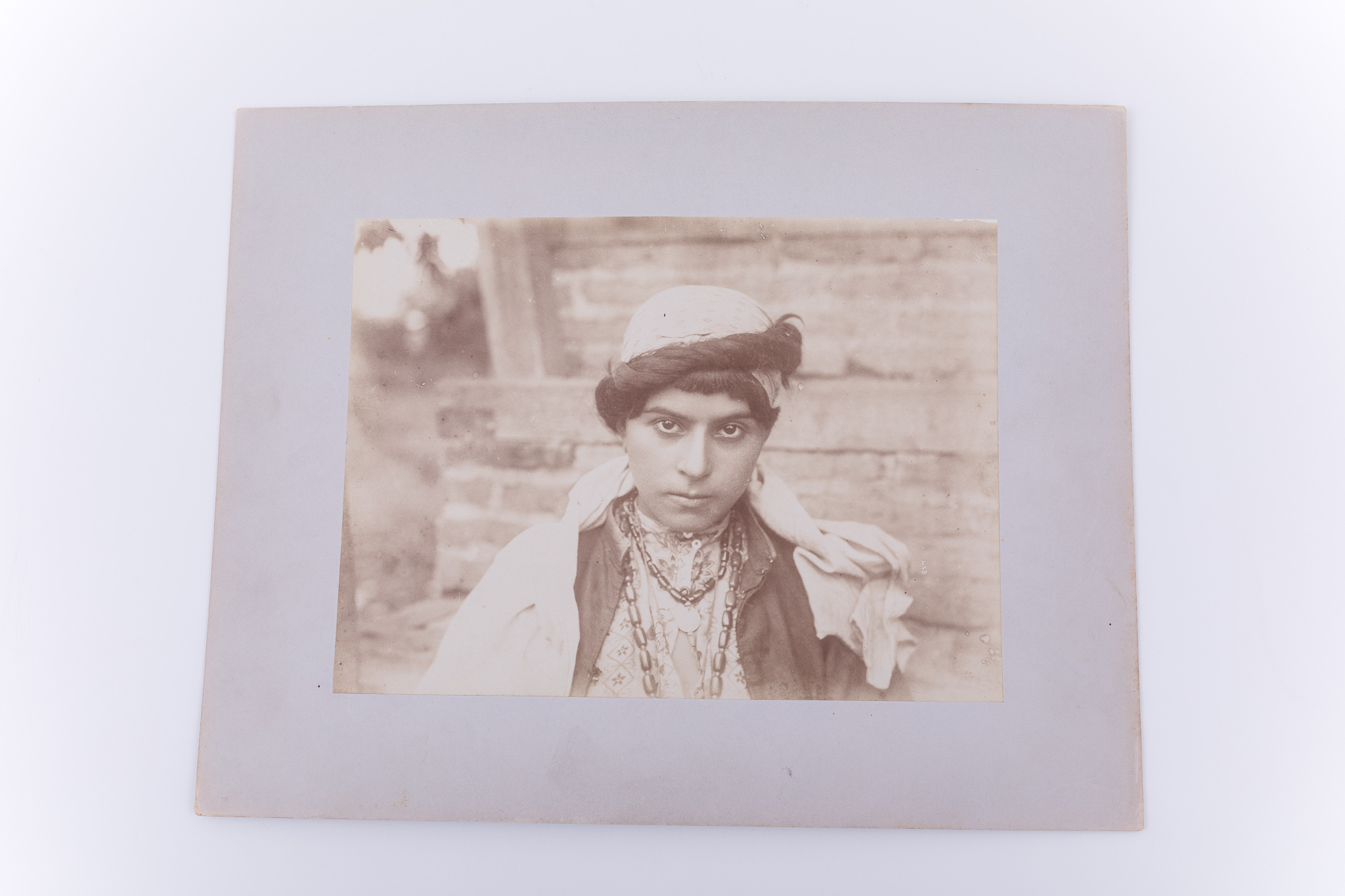 Fotografie de exterior ce prezintă o femeie în costum specifc comunității dervish din Persia. Imaginea este realizată pe hârtie albuminată, după un clișeu pe sticlă și este lipită pe un carton gros, de culoare gri. Pe clișeu, însemnare manuscrisă cu numărul clișeului „458” (practică frecventă în opera lui Antoin Sevruguin). Aceeași imagine apare în „The Myron Bement Smith Collection. Freer Gallery of Art and Arthur M. Sackler Gallery Archives. Smithsonian Institution, Washington, D.C.” (Nr. Inv. FSA A.4 2.12.GN.46.08). Fotografia din colecția Muzeului ASTRA face parte dintr-un album ce conține 51 de piese, realizate pe hârtie albuminată, aparținând lui Antoin Sevruguin. Acestea prezintă tipuri umane, peisaje și arhitectura din Iran de la sfârșitul secolului al XIX lea și începutul secolului al XX lea, în perioada dinastiei Qajar. Pe coperta albumului, confecționat din imitație de piele roșie, apare textul „Teheran” realizat cu tuș auriu, prin presare, încadrat într-un paspartu cu modele persane, realizat tot prin presare. Pe verso, însemnare manuscrisă, în limba germană, parțial descifrabilă: „Nr. 12. / beim …”; ștampilă: Muzeul „Brukenthal” Sibiu / Nr. …; număr de inventar MCPR 2253.