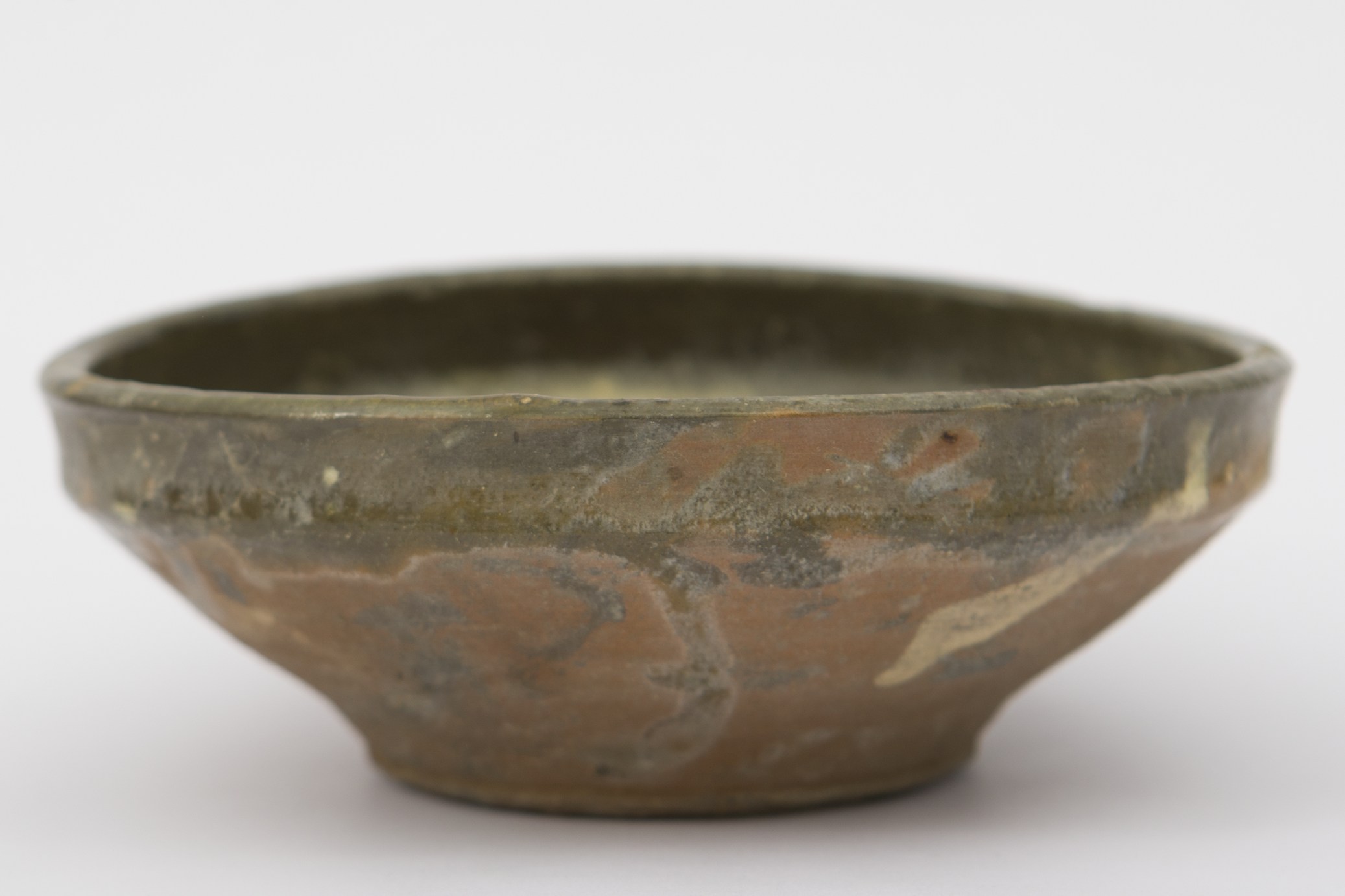 Piesă ceramică smălțuită de mici dimensiuni, având formă tronconică, cu fundul plat, pereții lărgiți înspre gură și buza ușor răsfrântă. În urma modelării la roată, interiorul strachinei a căpătat câteva inele circulare, dispuse pe pereții evazați. Decorul pictural este format din motive geometrice neregulate de vopsea verde, galbenă și neagră. Strachină era folosită în gospodărie pentru servirea hranei. Prezintă uzură funcțională. Cromatică: fond: cărămiziu; motive: verde; galben; negru.