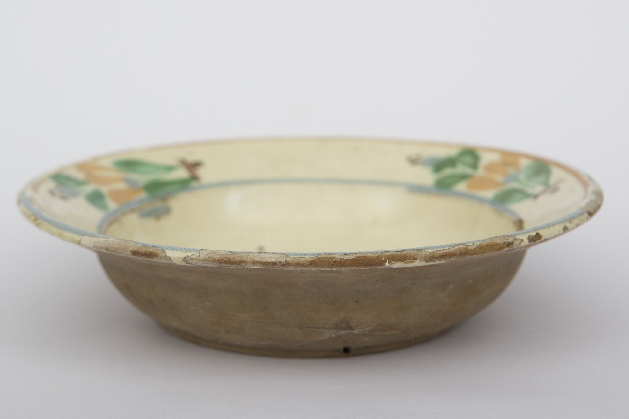 Vas ceramic smălțuit la interior, având formă tronconică, cu baza plată, pereții ridicați și buza profilată. Farfuria prezintă decor geometrizant și fitomorf, pictat peste stratul alb de angobă. Pe fundul vasului sunt dispuse două flori maro deschis, cu mijlocul albastru și încadrat de frunze verzi și linii negre. Pe buza piesei, între trei linii circulare, au fost dispuse circular trei motive florale cu frunze și petale verzi, albastre și maro deschis. La baza florilor linii scurte drepte, iar în vârf câte trei puncte negre. Farfuria era folosită ornamentarea interioarelor. Prezintă uzură funcțională. Cromatică: fond: cărămiziu; alb; motive: verde; maro; albastru.