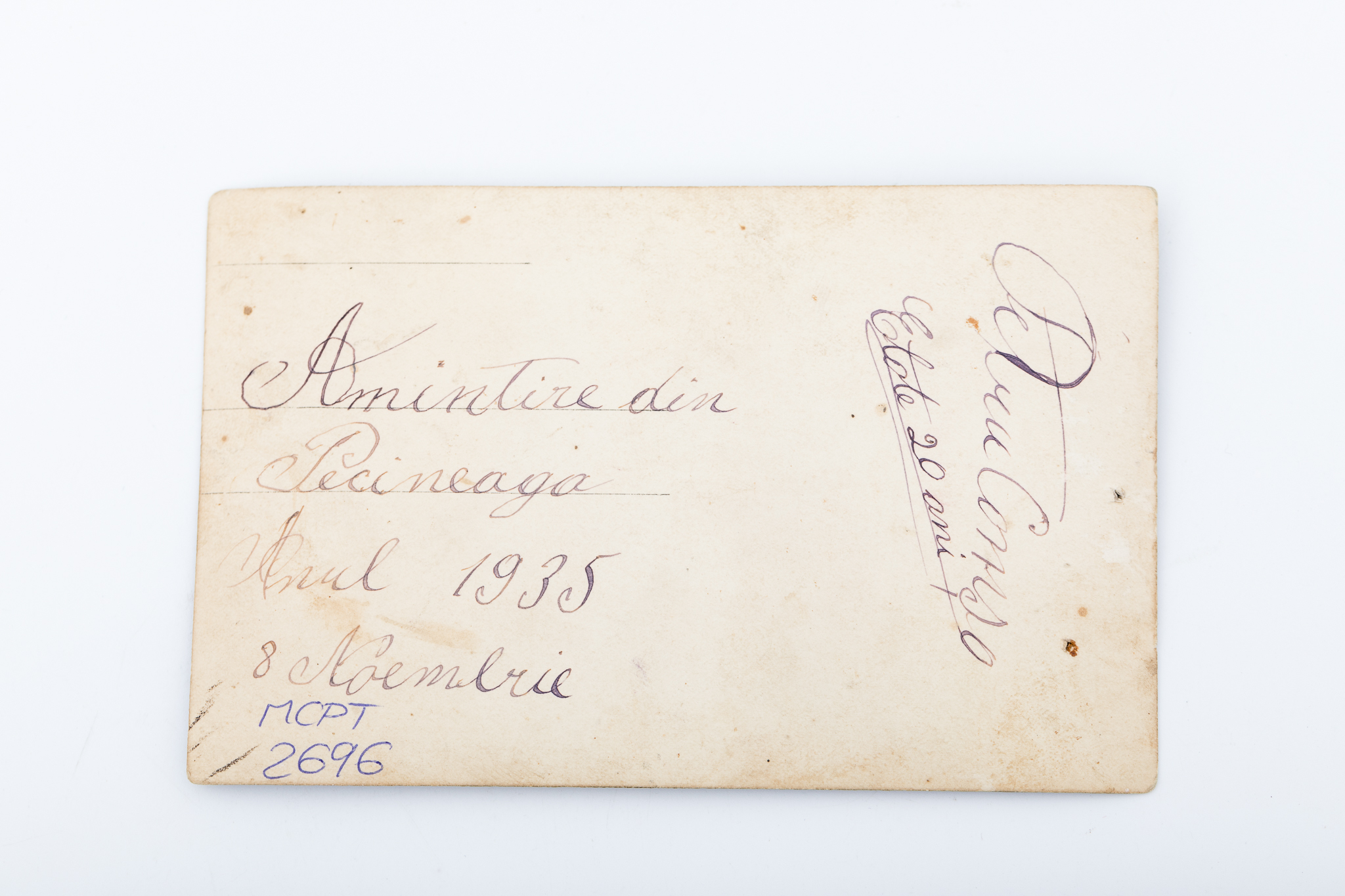 Fotografie realizată într-un atelier improvizat, cu elemente de recuzită: masă, buchet de flori, pancardă cu inscripția: „Suvenir / din Pecineaga 1935 (?)”. Prezintă un tânăr, pe Petru Comșa, în costum populare de sărbătoare. Imaginea este imprimată pe hârtie fotografică, cu gelatino-bromură de argint, în format Carte poștală, D.O.P.. Urme de uzură funcțională: colțurile îndoite, puncturi. V: Rubricatură de carte poștală. Însemnare manuscrisă: „Amintire din / Pecineaga / Anul 1935 / 8 Noembrie / Petru Comșa / Etate 20 ani”. Număr de inventar MCPT 2696.
